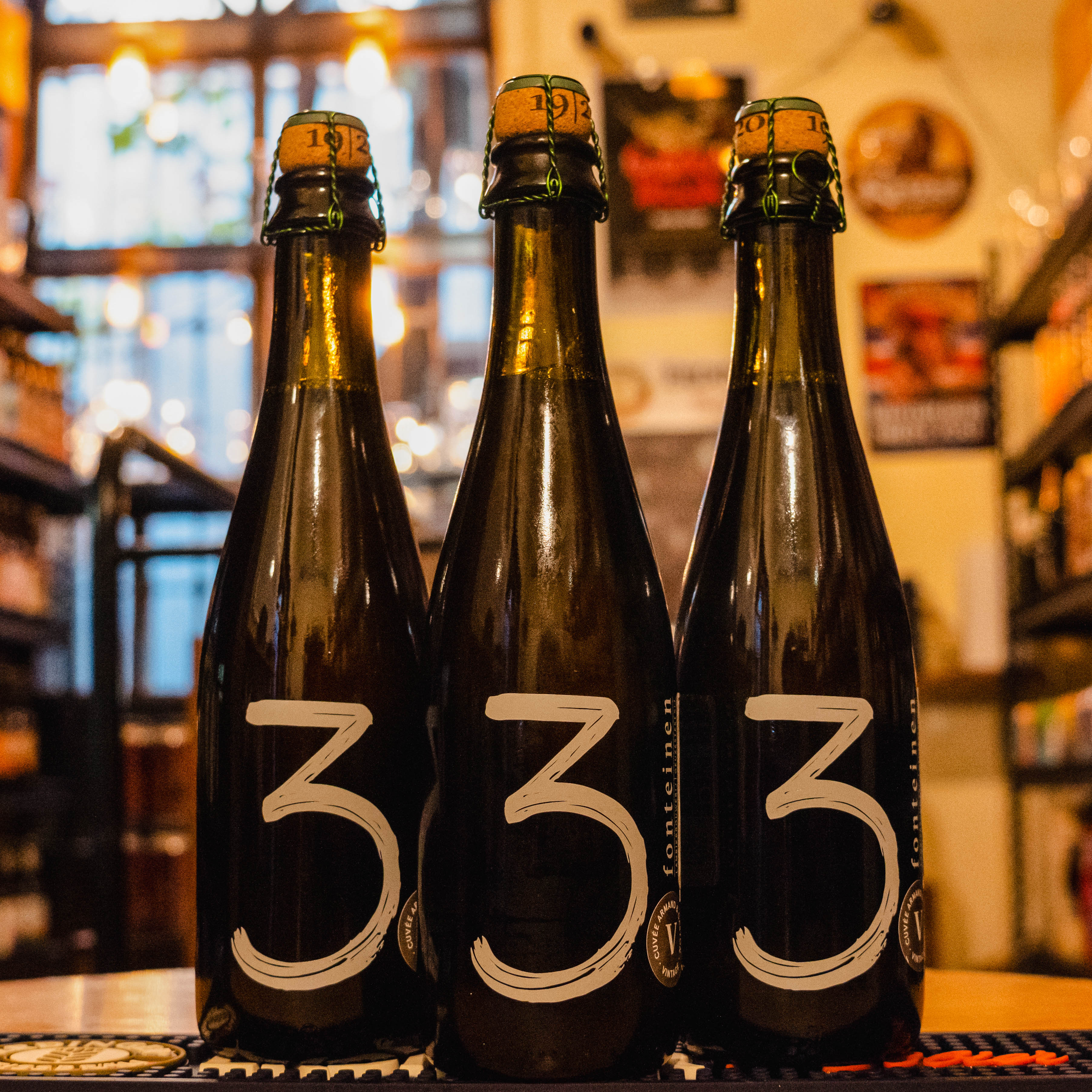 Botella de 3 Fonteinen Cuvée Armand & Gaston, una cerveza de estilo gueuze lambic elaborada por Brouwerij 3 Fonteinen en Bélgica. La etiqueta es verde oscura con tipografía clásica en blanco y dorado, destacando el nombre de la cerveza. ABV de 6.5%, con sabores complejos de frutas agrias y madera envejecida. Ideal para acompañar quesos fuertes y mariscos. El diseño de la botella refleja una estética tradicional belga.