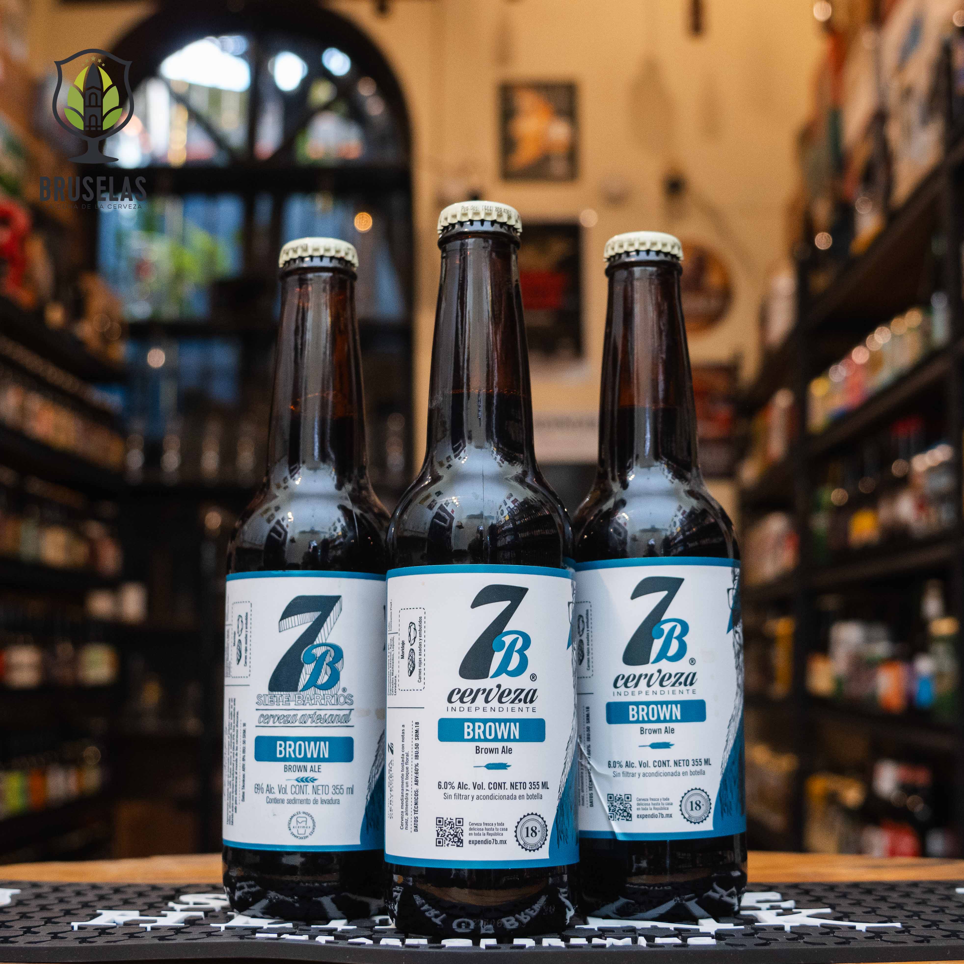 Botella de 7 Barrios Brown, una English Brown Ale de Cervecería 7 Barrios, San Luis Potosí. Con un ABV de 6.1%, presenta aromas suaves y frutales. Su sabor destaca notas de café, caramelo y frutos secos, con cuerpo medio-alto y baja carbonatación. Ideal para maridar con carnes rojas asadas y embutidos madurados. Presentación en botella de 355 ml, reflejando su carácter artesanal.