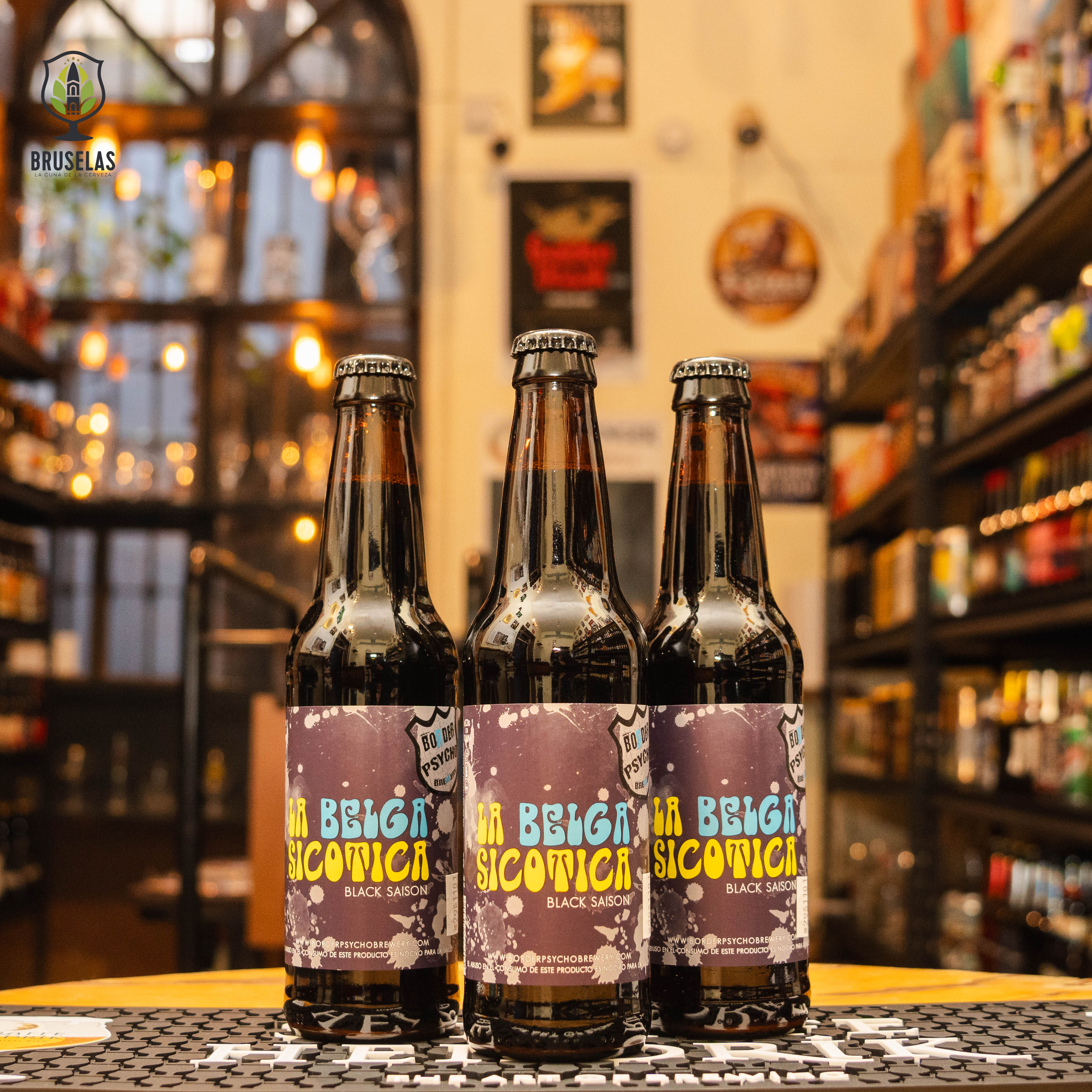 Botella de Belga Sicótica, una Black Saison de Border Psycho Brewery, elaborada en Tijuana, Baja California. La etiqueta tiene un diseño oscuro y audaz, reflejando su carácter intenso. Con un ABV de 7.0%, ofrece aromas terrosos y especiados con un toque de malta, y un cuerpo aterciopelado y bien balanceado. Ideal para acompañar carnes asadas, quesos maduros y platos especiados. Su diseño refleja una interpretación moderna y compleja del estilo belga.