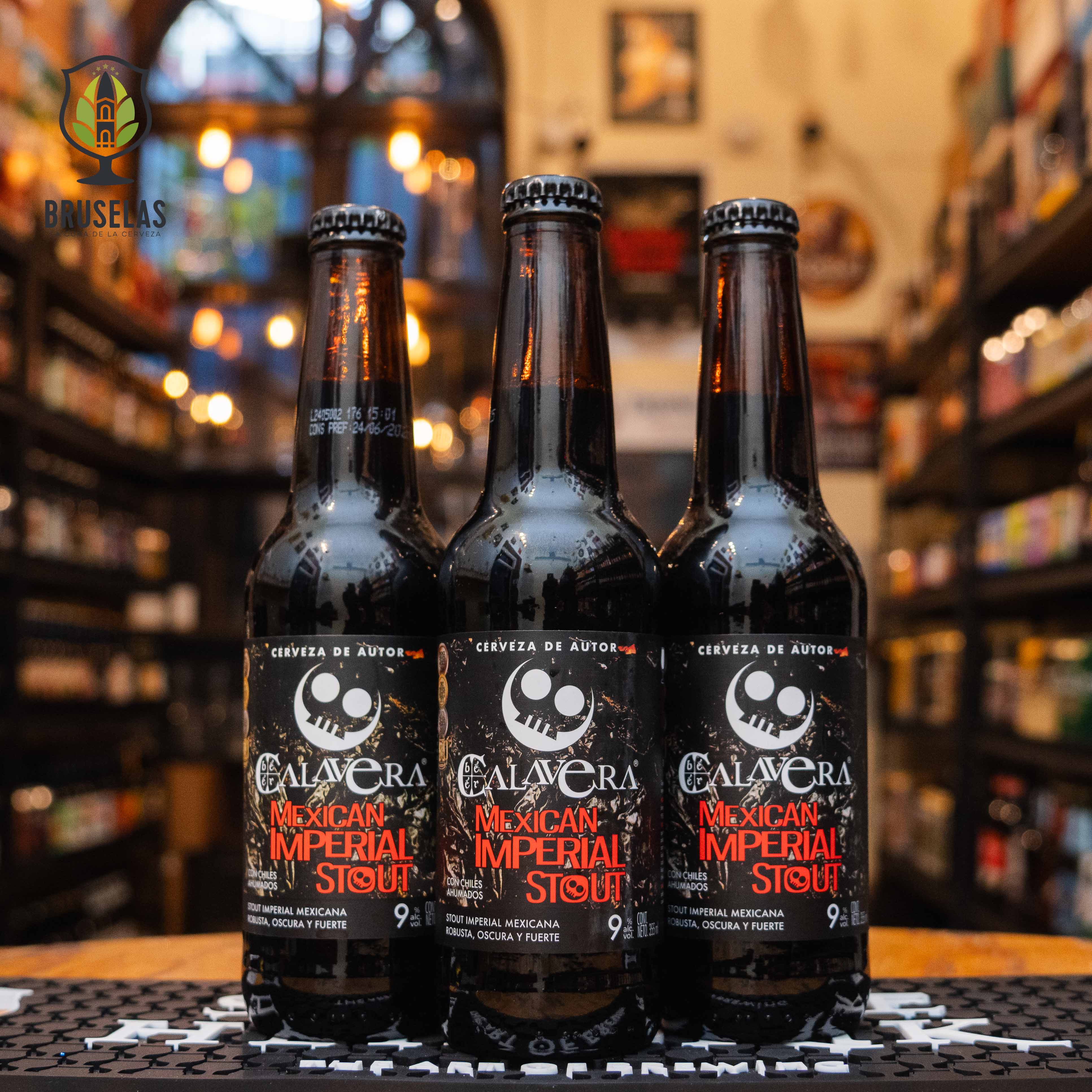 Botella de Mexican Imperial Stout de Cervecería Calavera, una stout robusta con 9% ABV. La etiqueta negra muestra una calavera blanca y detalles en rojo. Ofrece sabores intensos de chocolate amargo, café tostado y un toque sutil de chile. Ideal para maridar con postres de chocolate o carnes asadas. El diseño refleja su carácter artesanal oscuro y complejo.