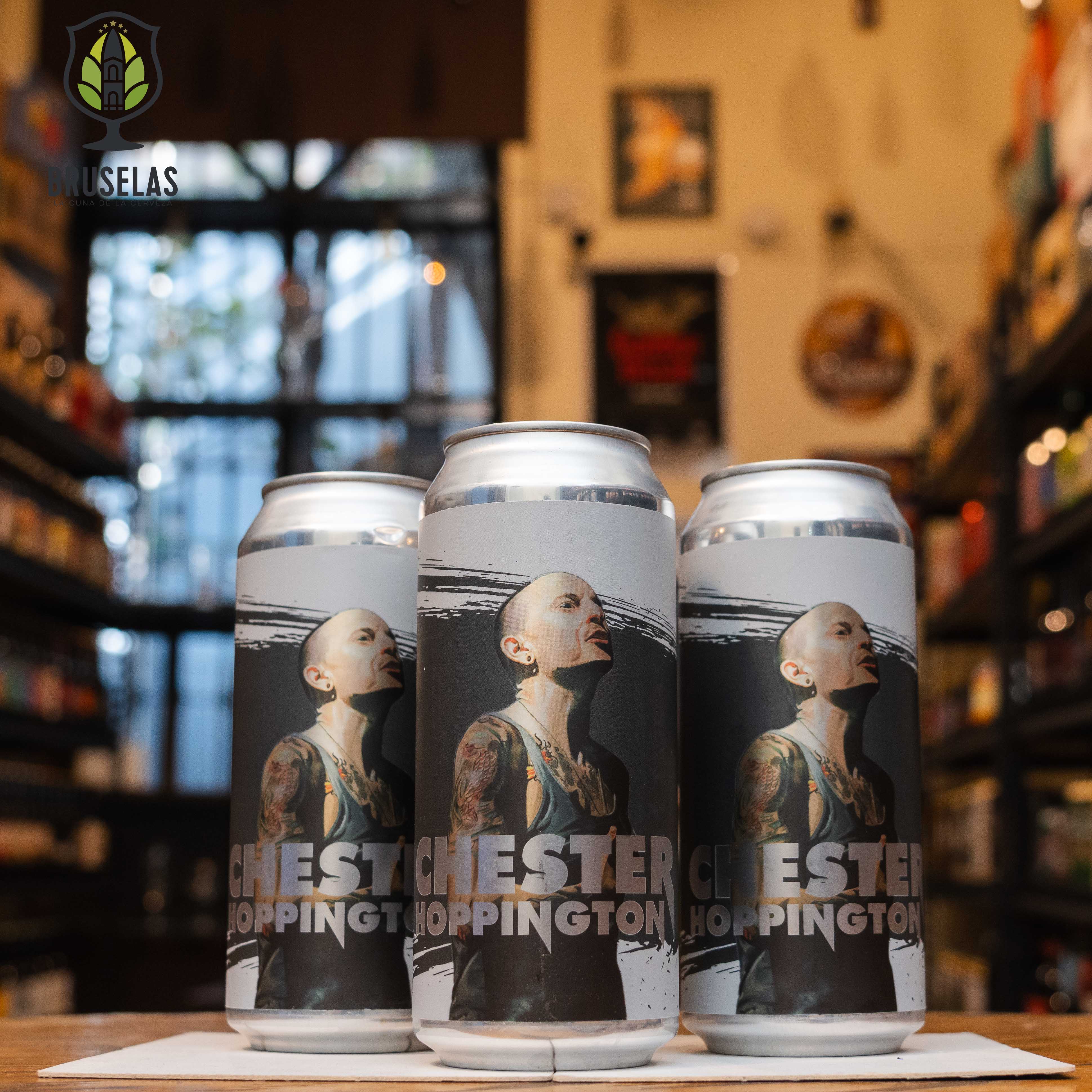 Lata de Chester Hoppington, una Triple New England IPA de Cervecería Rey Árbol con un ABV de 10.5%. La etiqueta presenta a Chester Bennington, vocalista de Linkin Park. Elaborada con lúpulos Citra, Mosaic y El Dorado, ofrece aromas tropicales y resinosos, con sabores de piña, mango y un amargor equilibrado. Ideal con carnes asadas y quesos fuertes.