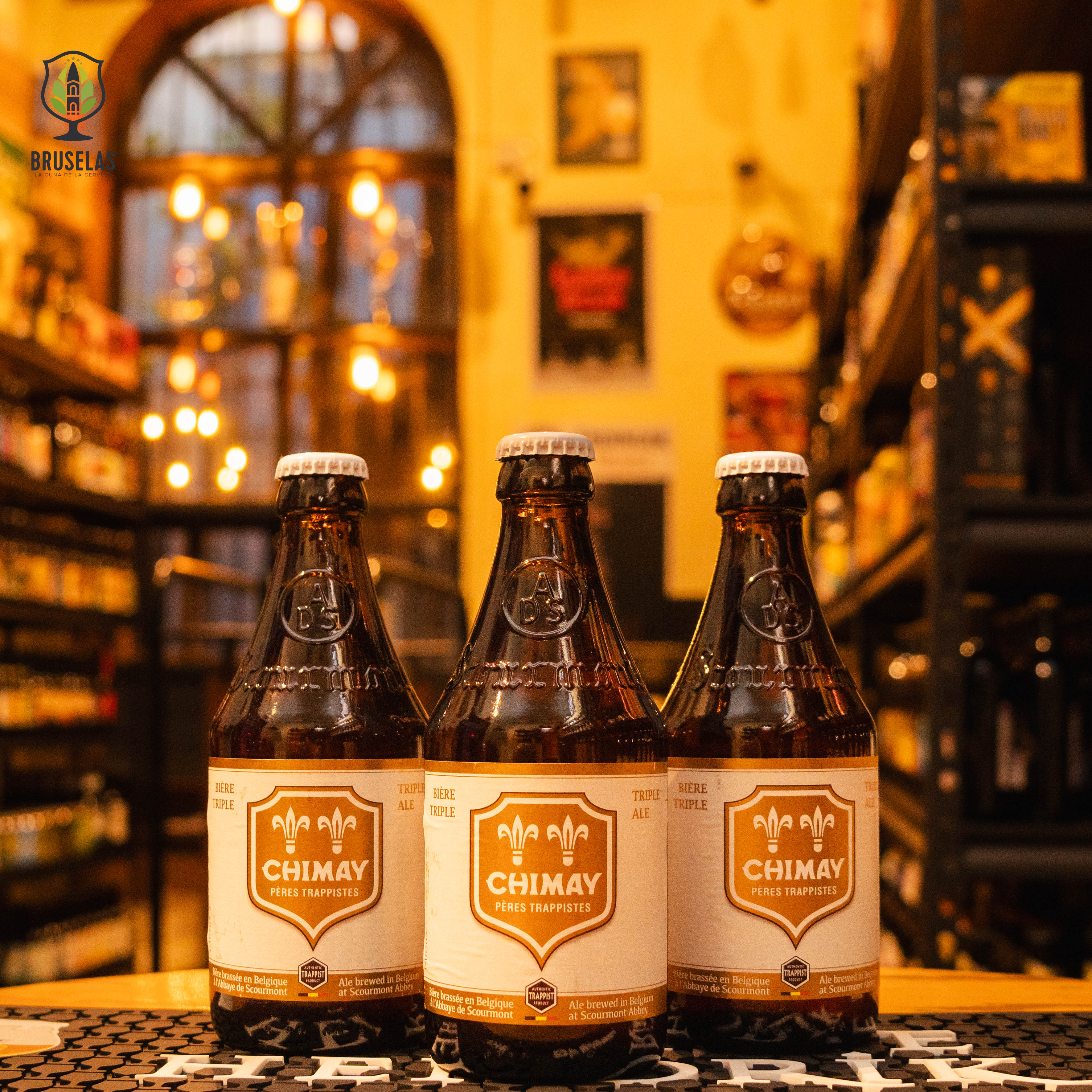 Botella de Chimay White, también conocida como Chimay Triple, una Belgian Tripel de la Abbaye de Scourmont. Con un ABV de 8%, presenta un color dorado con reflejos ámbar y espuma persistente. Ofrece aromas de cítricos, hierbas florales y un toque especiado. Su sabor es equilibrado, iniciando con dulzura suave que evoluciona hacia un amargor moderado, con un final seco. Ideal para acompañar pescados, mariscos y platos de curry.