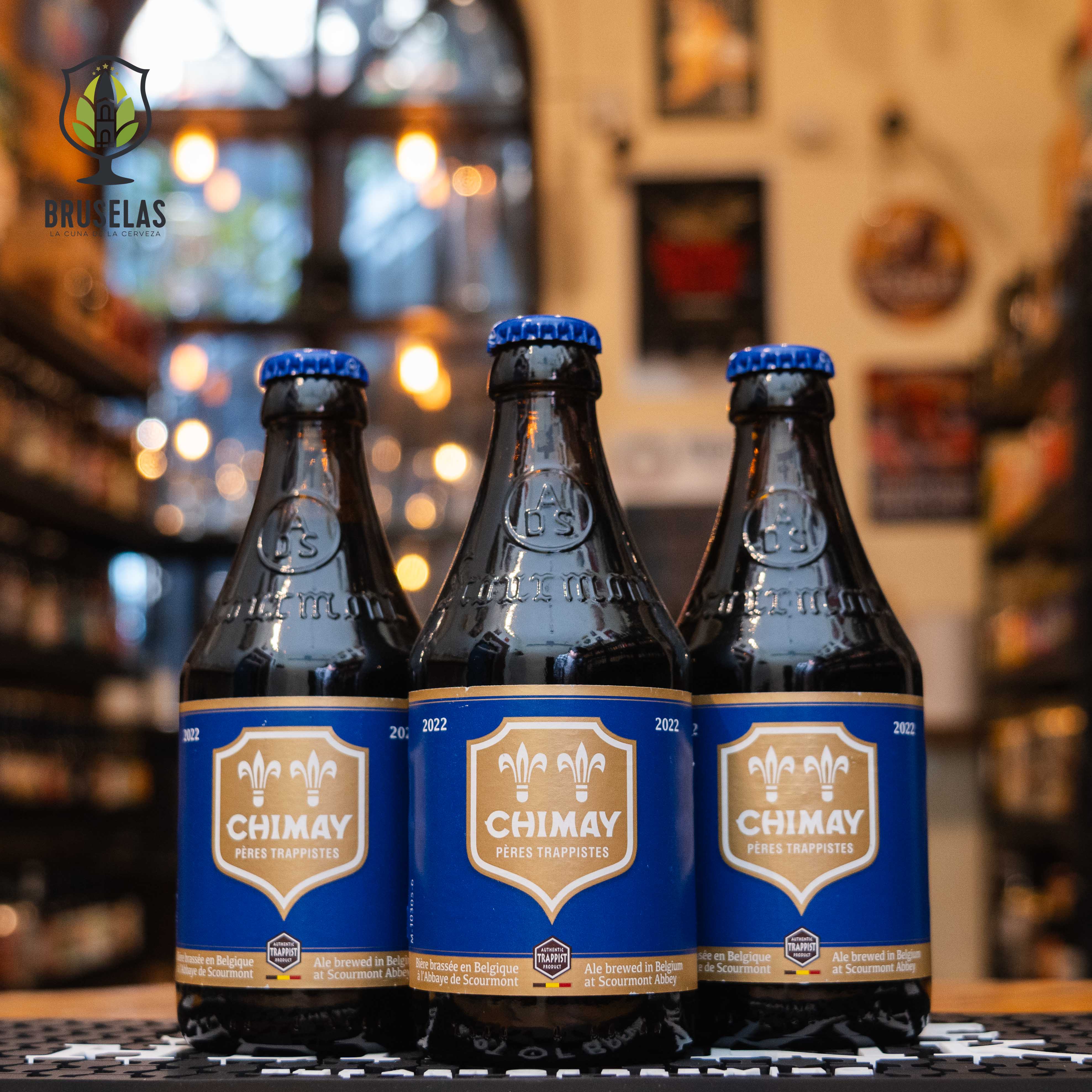 Botella de Chimay Bleue, también conocida como Grande Réserve, una Belgian Strong Dark Ale de Abbaye de Scourmont. Con un ABV de 9%, tiene un color marrón oscuro y espuma cremosa. Ofrece aromas de frutas oscuras, especias y levadura, con sabores de malta tostada, caramelo y un final ligeramente amargo. Ideal para quesos fuertes, estofados de carne y postres de chocolate oscuro.