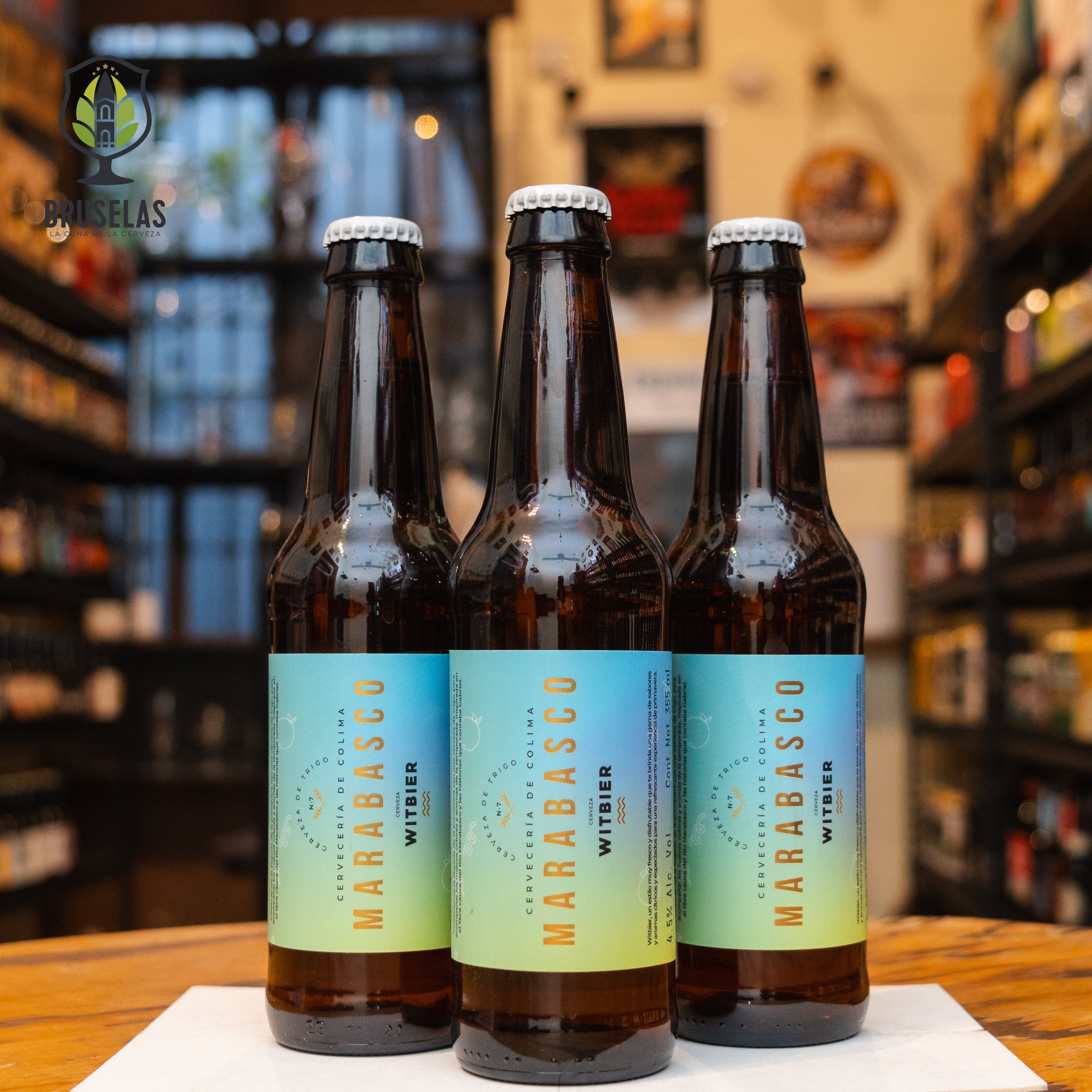 Botella de Colima Marabasco, una Witbier de la Cervecería de Colima, inspirada en el estilo belga. Con un ABV de 4.5%, es refrescante y especiada, con aromas de cáscara de naranja, cilantro y notas florales. Su sabor combina toques cítricos y especiados, perfecta para maridar con mariscos frescos, ensaladas y platos con salsas cítricas. Presentación en botella de 355 ml, ideal para climas calurosos.