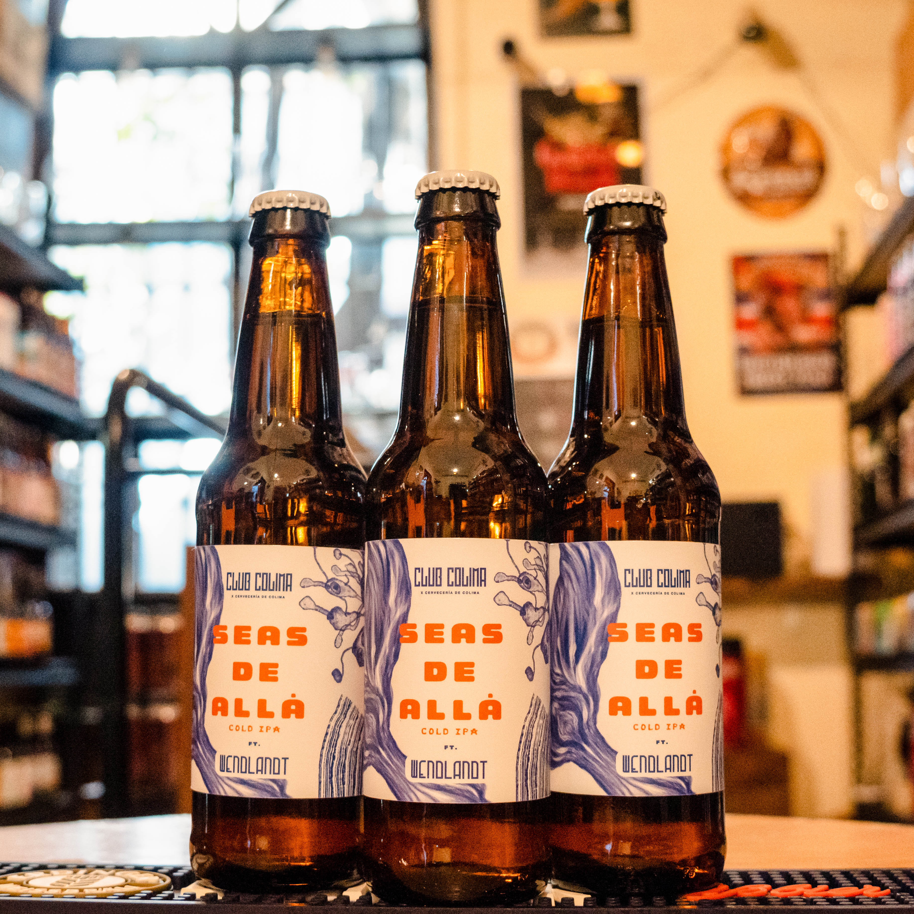 Botella de Colima Seas de Allá, una Cold IPA colaborativa entre Cervecería de Colima y Wendlandt. Con un ABV de 6.5%, presenta aromas frutales dominados por notas de maracuyá, guayaba y toronja. Su sabor es fresco y lupulado, con un amargor alto pero limpio y un final seco, lo que la hace extremadamente refrescante. Ideal para acompañar platos frescos como ceviches, ensaladas o tacos de pescado.