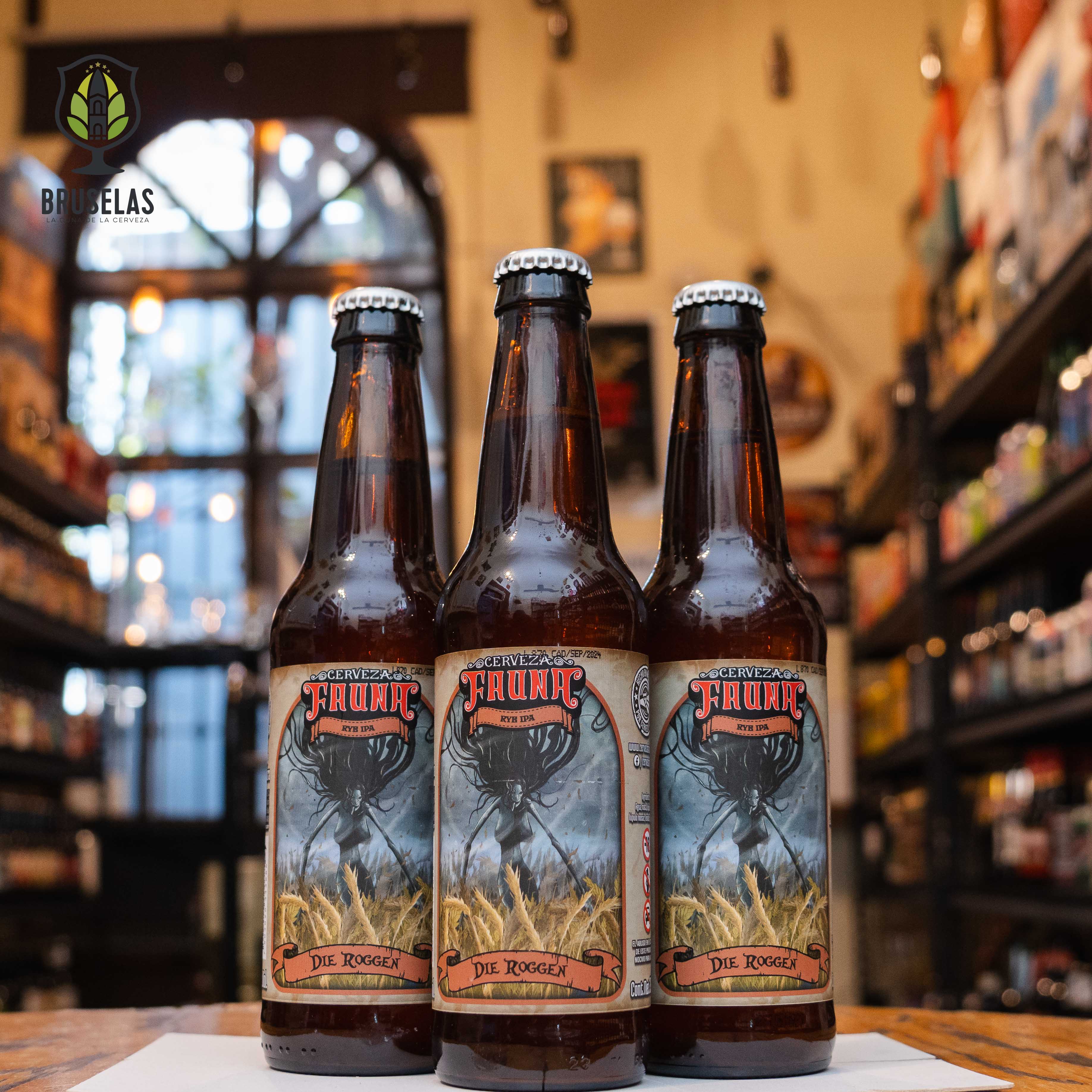 Botella de Fauna Die Roggen, una Rye IPA de Cervecería Fauna en Mexicali, Baja California. Con un ABV de 6.8% y 40 IBU, esta cerveza ámbar presenta un perfil complejo con notas de centeno, frutas tropicales como mango, piña y toronja, además de caramelo y pan. Su sabor comienza con una dulzura sutil y termina con un amargor especiado. Ideal para maridar con carnes ahumadas y quesos maduros. Presentación en botella de 355 ml.