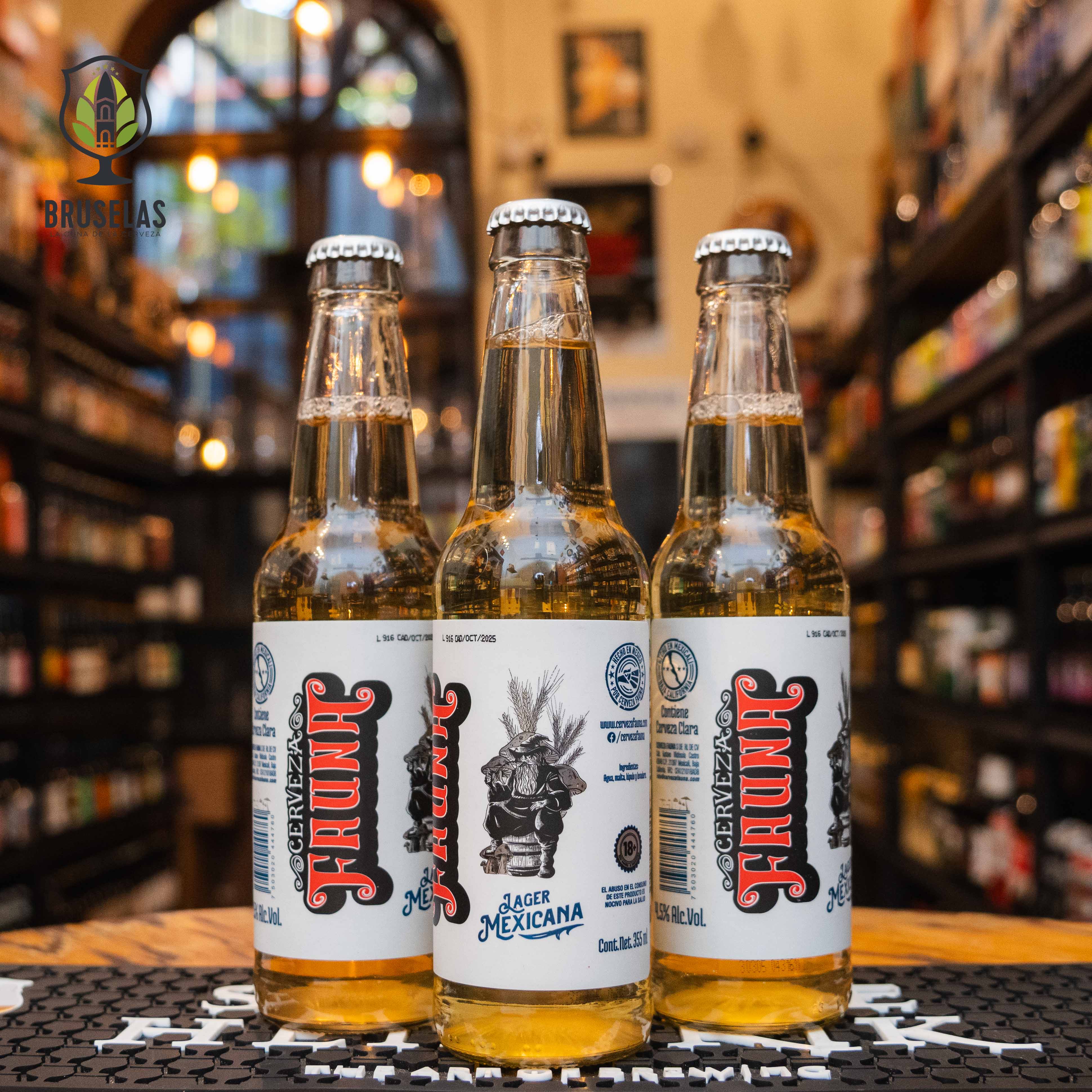 Botella de Fauna Lager Mexicano, una Lager elaborada por Cervecería Fauna en Mexicali, Baja California. Con un ABV de 4.5% y 10 IBU, es una cerveza ligera y refrescante, con aromas de malta, cereal, lúpulo y maíz. Su sabor es suave, con un toque dulce inicial y un final refrescante. Perfecta para acompañar comidas ligeras como ensaladas o mariscos, o disfrutar sola en un día caluroso. Presentación en botella de 355 ml.