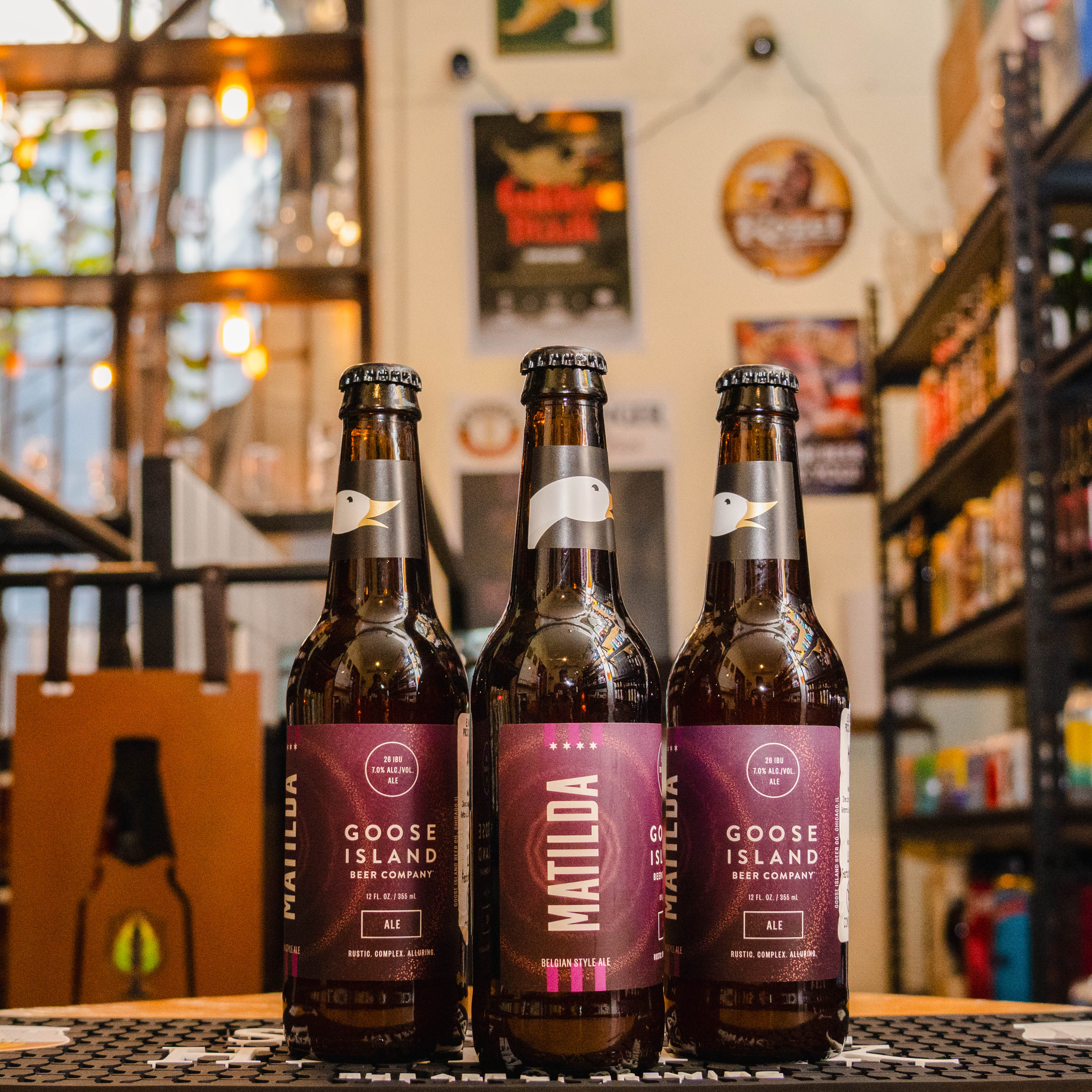 Botella de Matilda, una Belgian Strong Pale Ale de Goose Island Beer Co. La etiqueta presenta un diseño elegante en tonos cálidos, destacando el nombre de la cerveza en tipografía clara. Con un ABV de 7%, ofrece aromas florales y especiados, con notas de manzana, pera y levadura belga. Su sabor equilibra maltas dulces, caramelo y especias, con un final seco y ligeramente ácido. Ideal para maridar con quesos fuertes, carnes asadas y platos especiados.