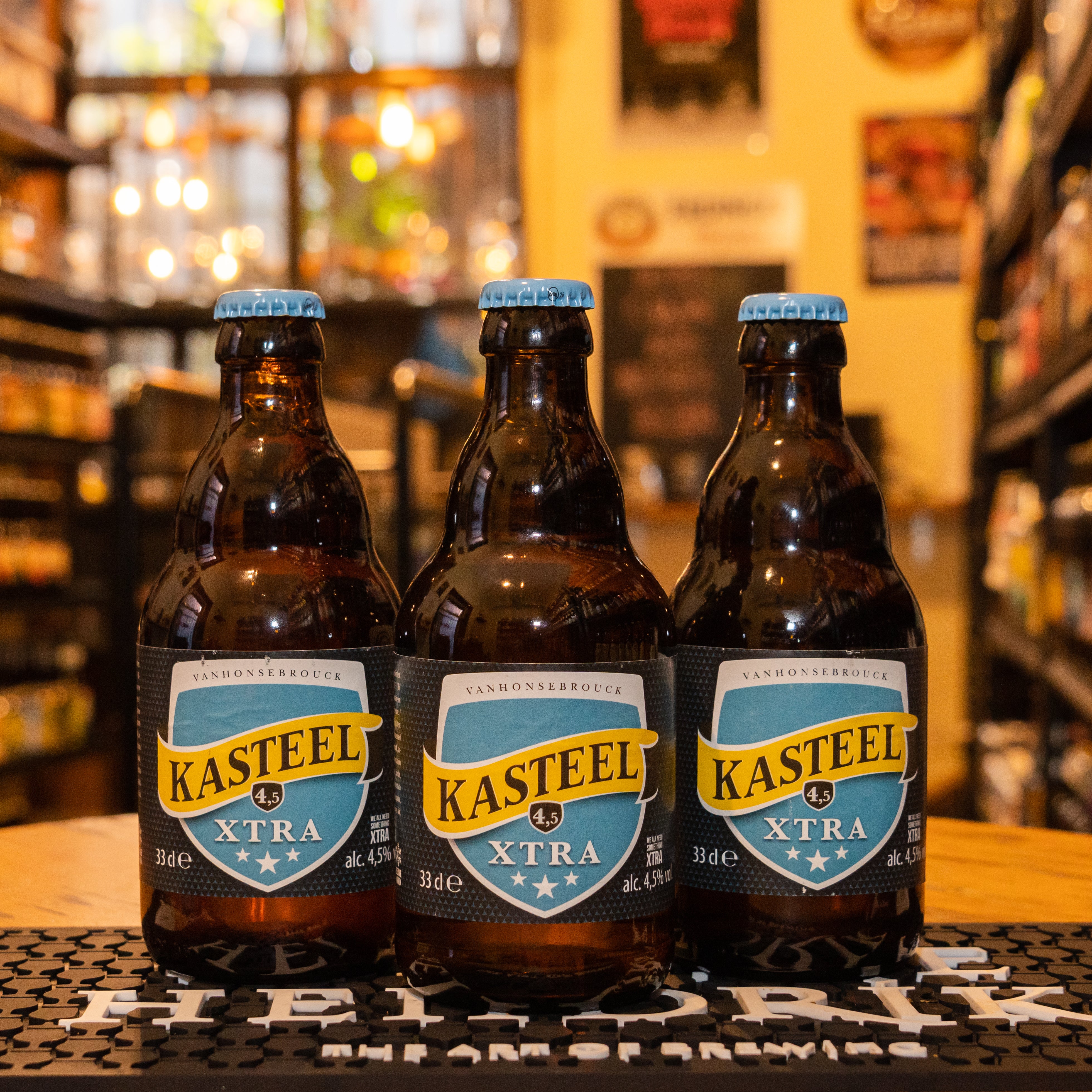 Botella de Kasteel Xtra, una Blonde Ale belga de la cervecería Van Honsebrouck. Con un ABV de 4.5%, presenta un color dorado pálido y espuma ligera. Ofrece aromas cítricos con notas de frutas tropicales y especias. Su sabor es equilibrado, con un suave amargor y un toque frutal. Ideal para maridar con ensaladas frescas, pescados y quesos suaves. El diseño refleja la frescura y ligereza de esta cerveza.