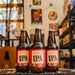 Botella de Lagunitas IPA, una India Pale Ale de Lagunitas Brewing Company. Con un ABV de 6.2%, esta cerveza se caracteriza por aromas frescos de cítricos y pino, con toques florales. Su sabor presenta un amargor equilibrado complementado con una suave base de malta, cítricos y matices de pino. Ideal para maridar con carnes a la parrilla, platos picantes y quesos maduros. Perfecta para quienes buscan una IPA lupulada y refrescante.