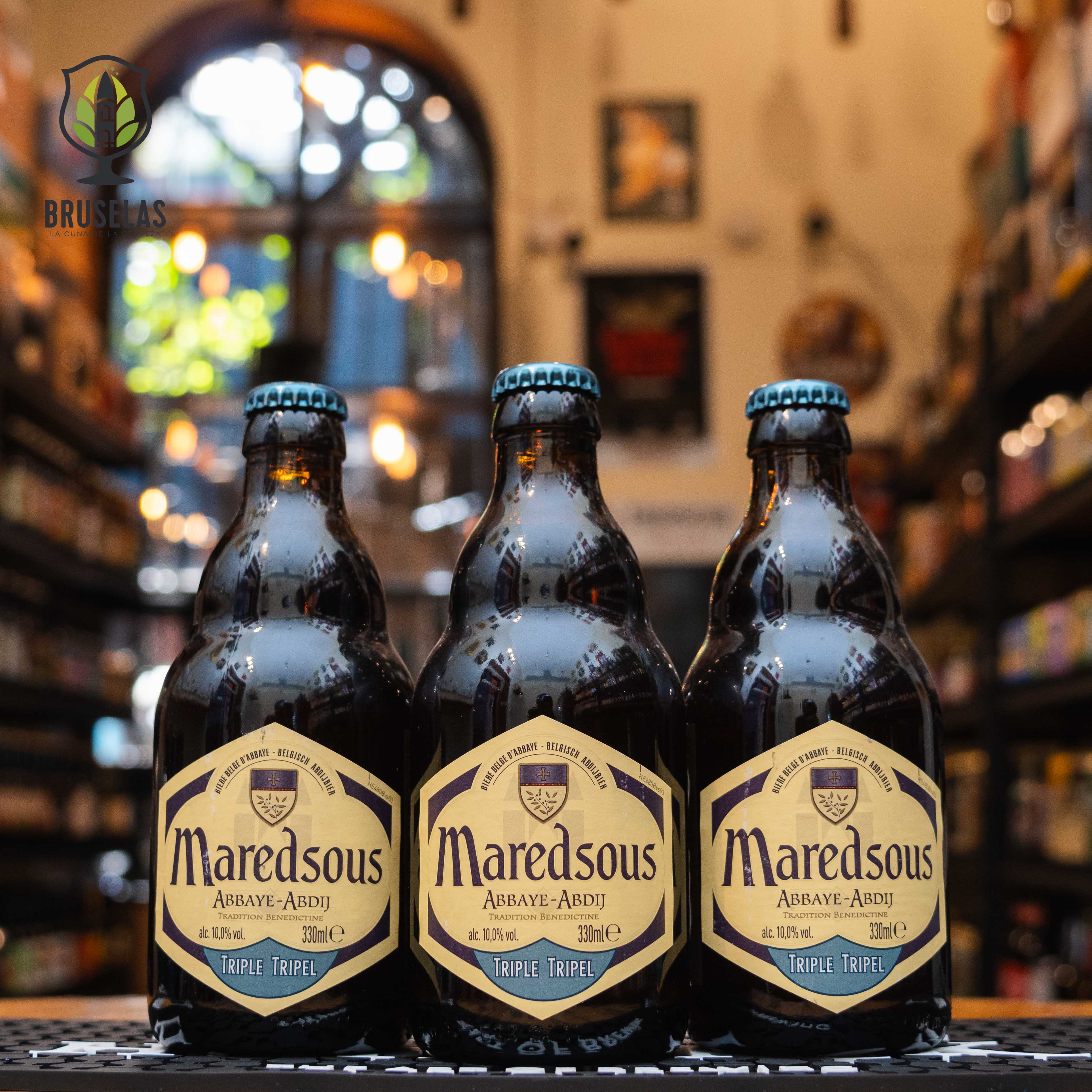 Botella de Maredsous 10 Tripel, una cerveza belga estilo Tripel de Brouwerij Duvel Moortgat NV. La etiqueta es de color crema con detalles en azul y marrón, destacando el nombre 'Maredsous' y el contenido alcohólico del 10%. Esta Tripel ofrece aromas de malta, levadura belga y especias, con un sabor seco y matices de alcohol. Ideal para acompañar carnes rojas, quesos maduros y cocina especiada.