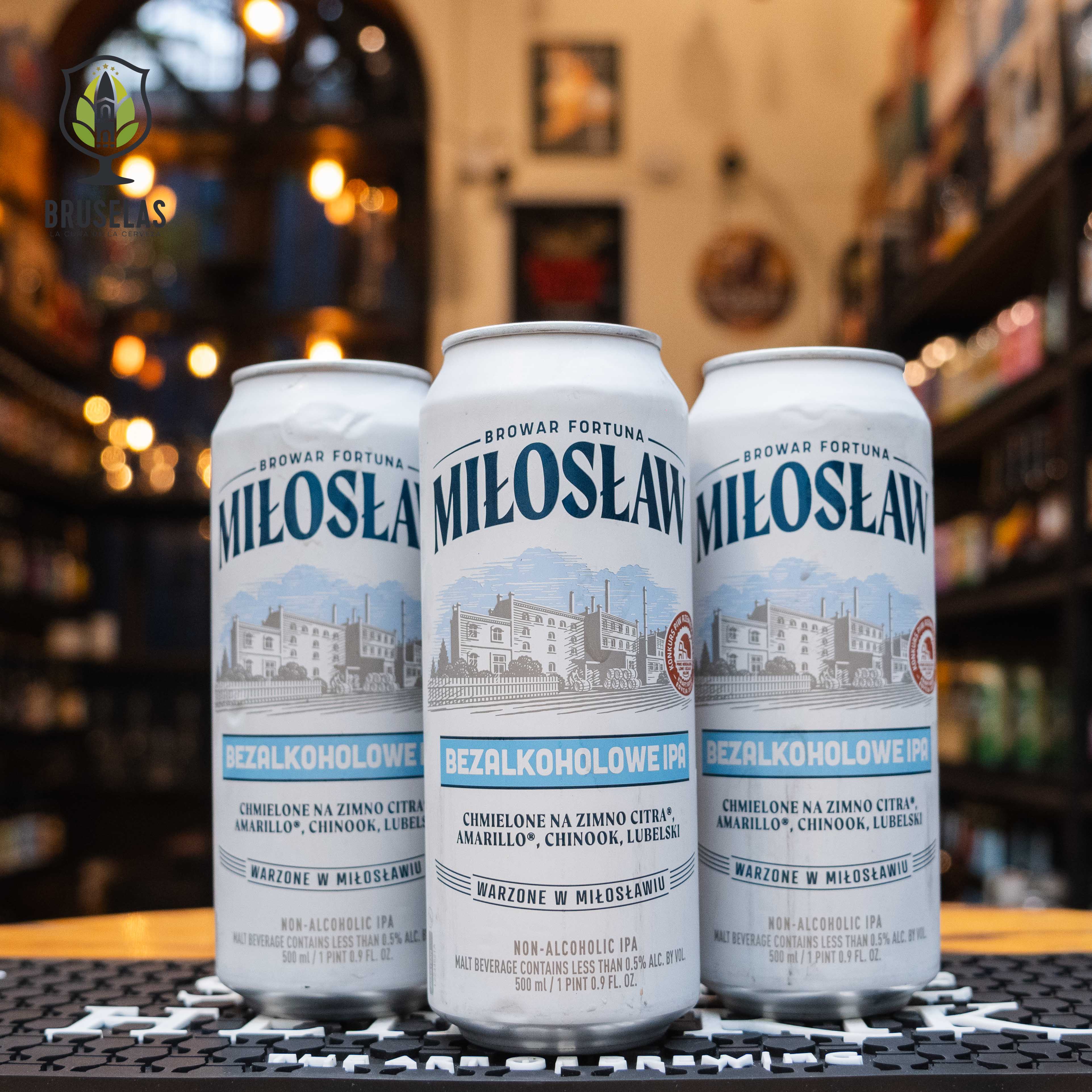 Lata de Miłosław Bezalkoholowe IPA, una cerveza sin alcohol estilo IPA elaborada por Browar Fortuna en Polonia. La etiqueta presenta un diseño en tonos blancos y azules, con ilustraciones del paisaje cervecero en el centro. Con un ABV de 0.5%, esta cerveza infusionada con lúpulos Citra, Amarillo, Chinook y Lubelski ofrece aromas cítricos y herbales, junto con un toque único de té Sencha Earl Grey. Ideal para maridar con ensaladas frescas, sushi o mariscos.