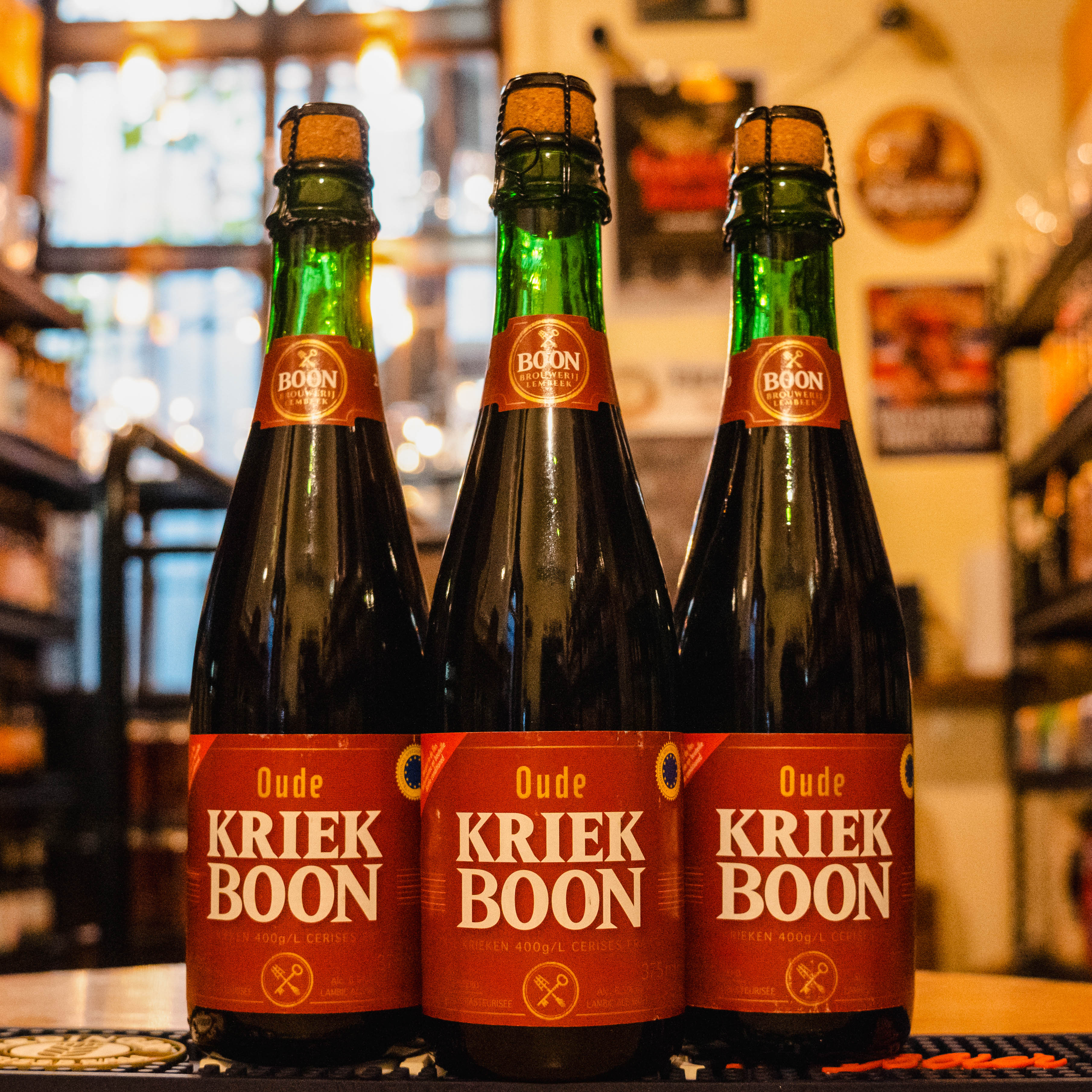 Botella de Boon Oude Kriek, una Lambic Kriek de Brouwerij Boon, elaborada en Bélgica. La etiqueta tiene un diseño tradicional en tonos rojos y dorados, reflejando el carácter afrutado de la cerveza. Con un ABV de 6.5%, ofrece aromas de cereza y frutas maduras con toques de barrica. Su sabor es intenso a cereza, con una acidez suave y refrescante. Ideal para acompañar quesos suaves, ensaladas con frutas y tartas de cereza. El diseño refleja su proceso artesanal y añejado en barrica.