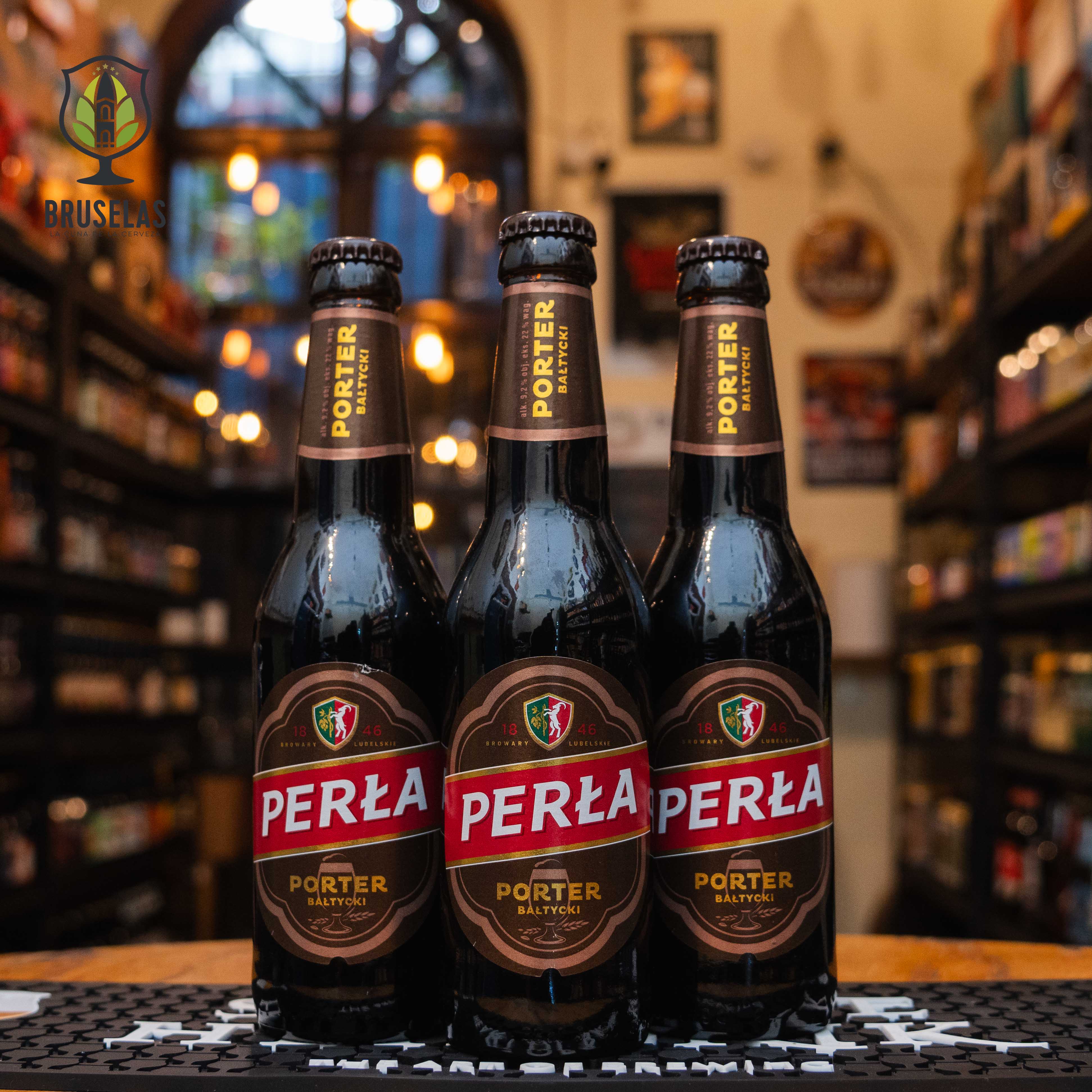 Botella de Perła Porter Bałtycki, una cerveza estilo Baltic Porter elaborada por Perła – Browary Lubelskie, Polonia. La etiqueta muestra el nombre "Perła" en letras blancas sobre un fondo rojo, enmarcado por detalles en marrón y dorado. Presenta un ABV de 9.2%, con sabores intensos de chocolate, caramelo y café, acompañados de un final ligeramente dulce y amargo. Ideal para acompañar carnes ahumadas y postres de chocolate.