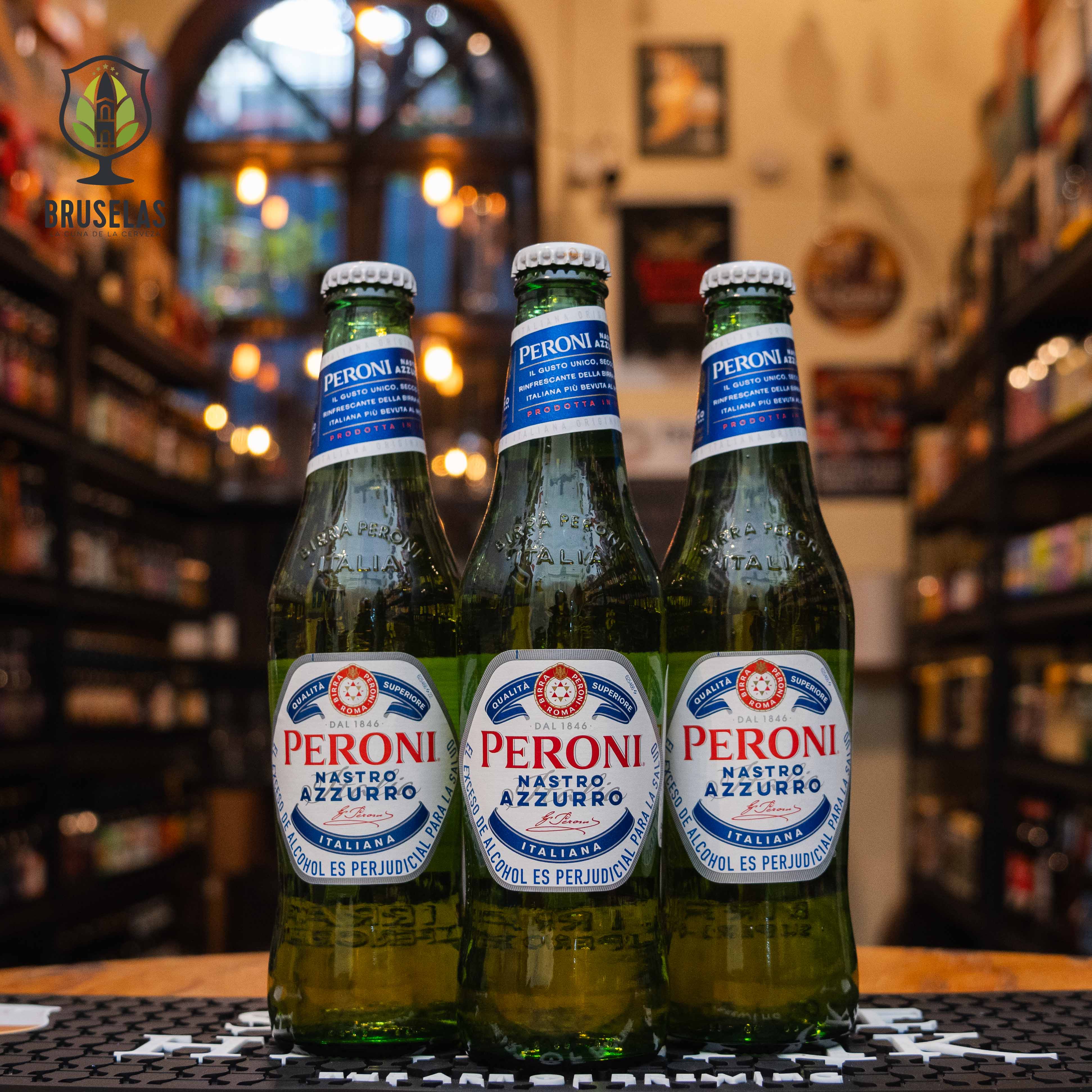 Botella de Peroni Nastro Azzurro, una cerveza tipo lager elaborada por Birra Peroni, Italia. La etiqueta es blanca y azul con detalles rojos, resaltando el nombre "Peroni Nastro Azzurro" en el centro, con una banda azul en la parte superior. Presenta un ABV de 5.1%, ofreciendo un sabor refrescante y ligero, con un amargor suave y final limpio. Ideal para acompañar ensaladas, pastas y mariscos.