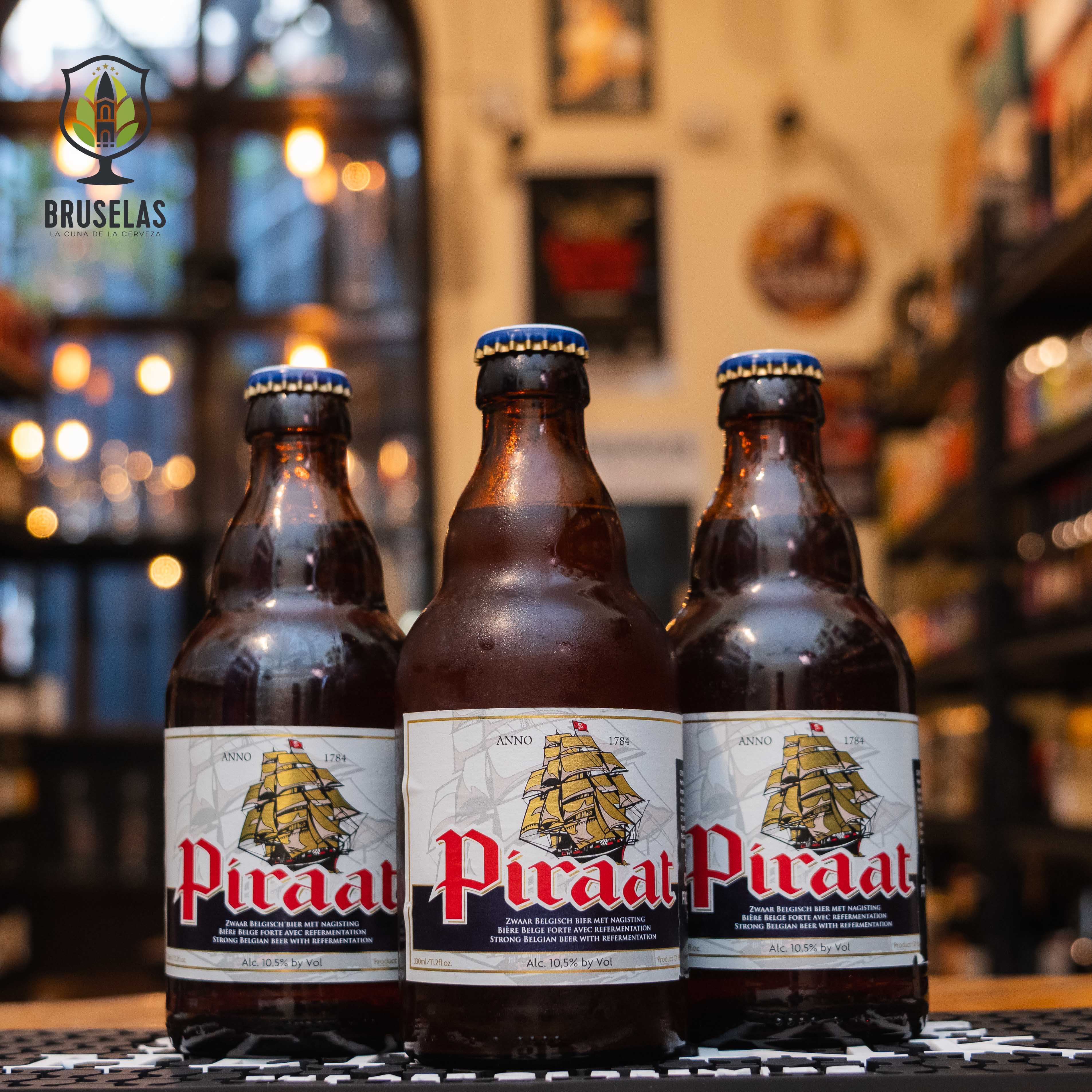 Botella de Piraat, una cerveza estilo Belgian Strong Pale Ale elaborada por Van Steenberge, Bélgica. La etiqueta muestra un barco pirata dorado sobre un fondo claro, con el nombre "Piraat" en letras rojas destacadas. Presenta un ABV de 10.5%, ofreciendo un perfil de sabor robusto, con notas de malta dulce, especias y un toque frutal. Ideal para acompañar carnes asadas y quesos fuertes.