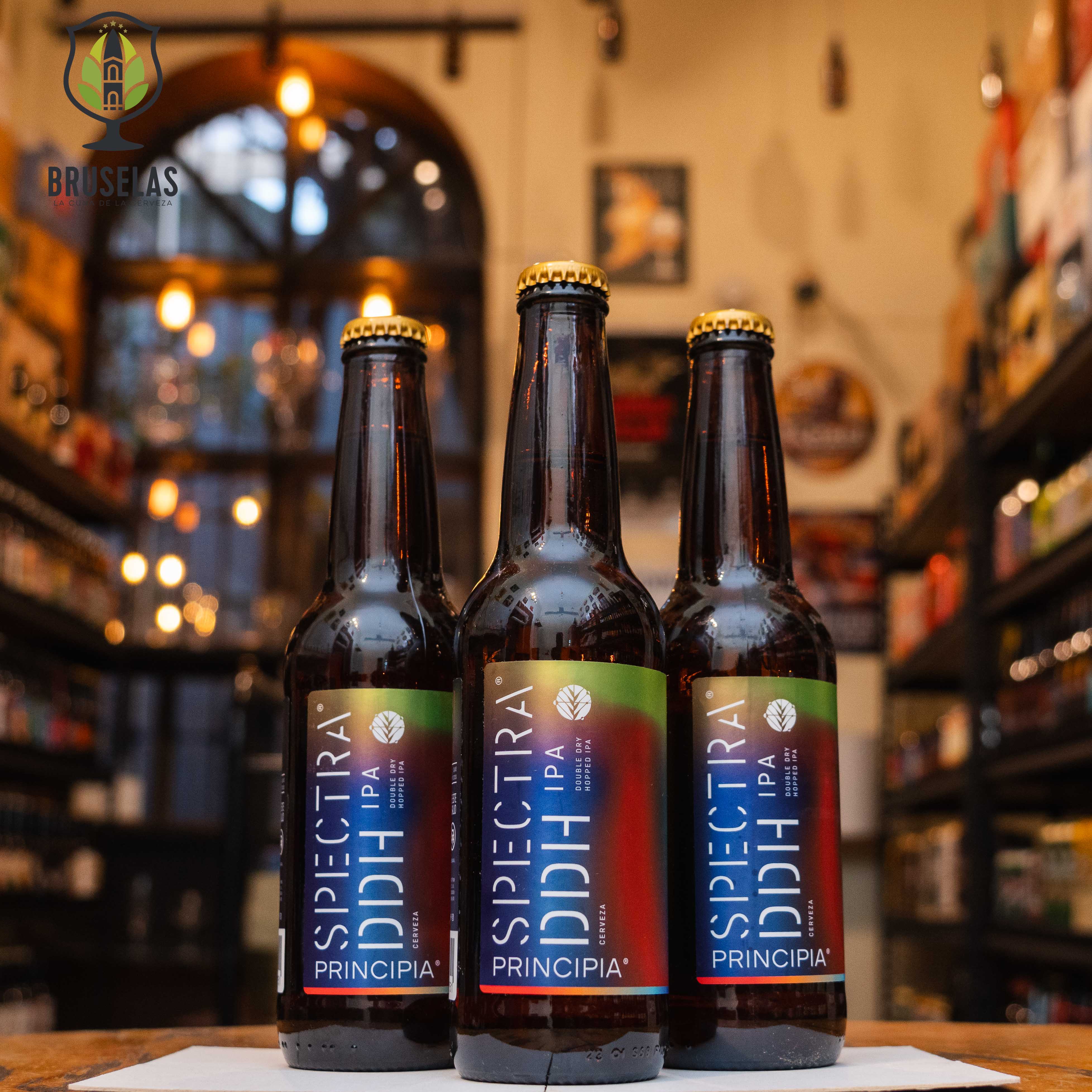 Botella de Principia DDH Spectra, una Double Dry Hopped IPA de Cervecería Principia con un ABV de 6.7%. Ofrece aromas intensos de frutas tropicales y cítricas con un toque herbal de lúpulo. Su sabor es equilibrado entre lo cítrico y lo tropical, con un amargor suave. Ideal para maridar con pizzas, pollo a las brasas y mariscos. Refleja una experiencia frutal y bien equilibrada, perfecta para los amantes de las IPAs.