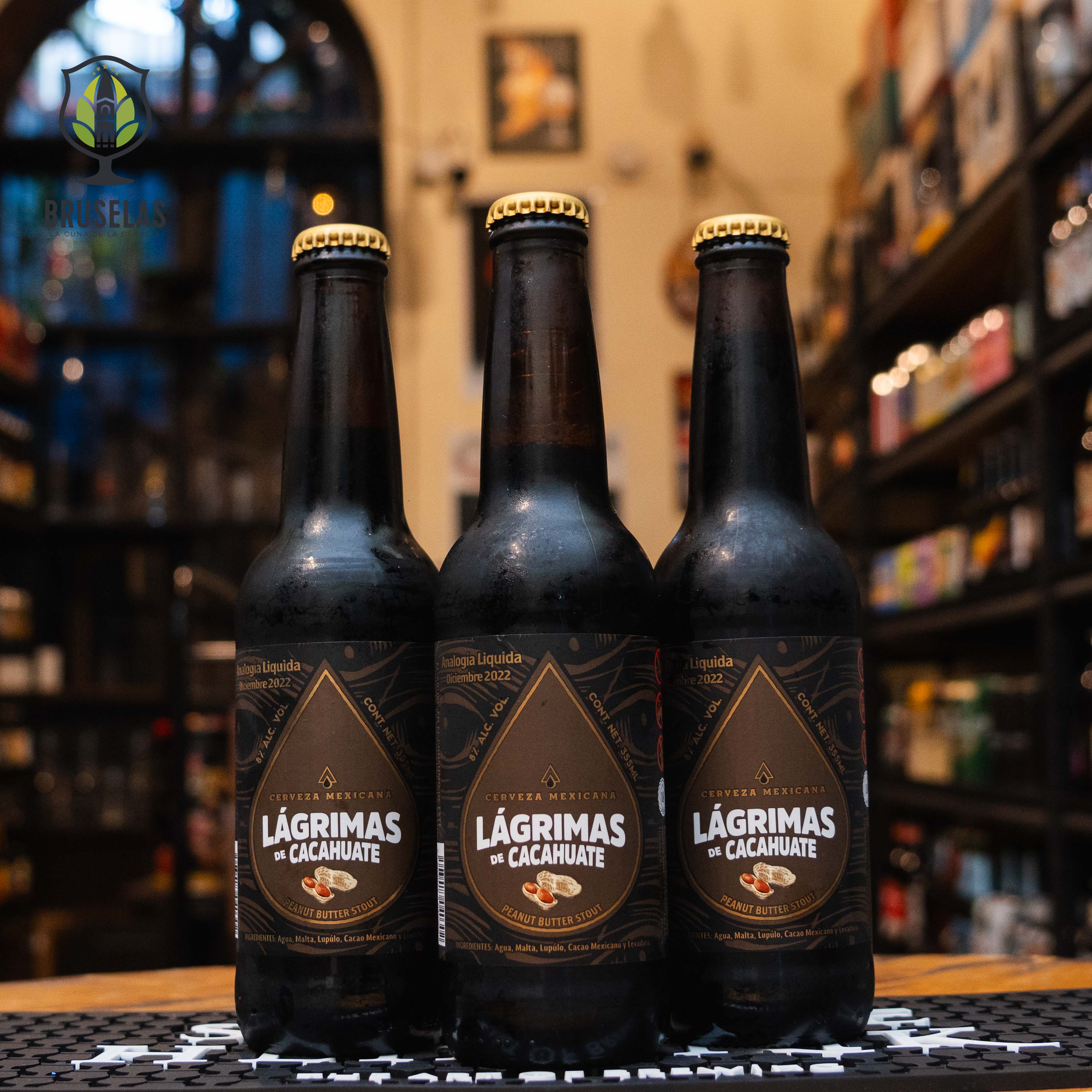 Botella de Rámuri Lágrimas de Cacahuate, una cerveza artesanal estilo Peanut Butter Stout elaborada por Cervecería Rámuri en Tijuana, Baja California, México. La etiqueta presenta un diseño oscuro con detalles dorados y el nombre "Lágrimas de Cacahuate" en tipografía blanca. Presenta un ABV de 8%, destacando aromas de cacahuate tostado, chocolate y café. Su sabor balanceado y textura sedosa la hacen ideal para acompañar postres como brownies de chocolate o carnes rojas.