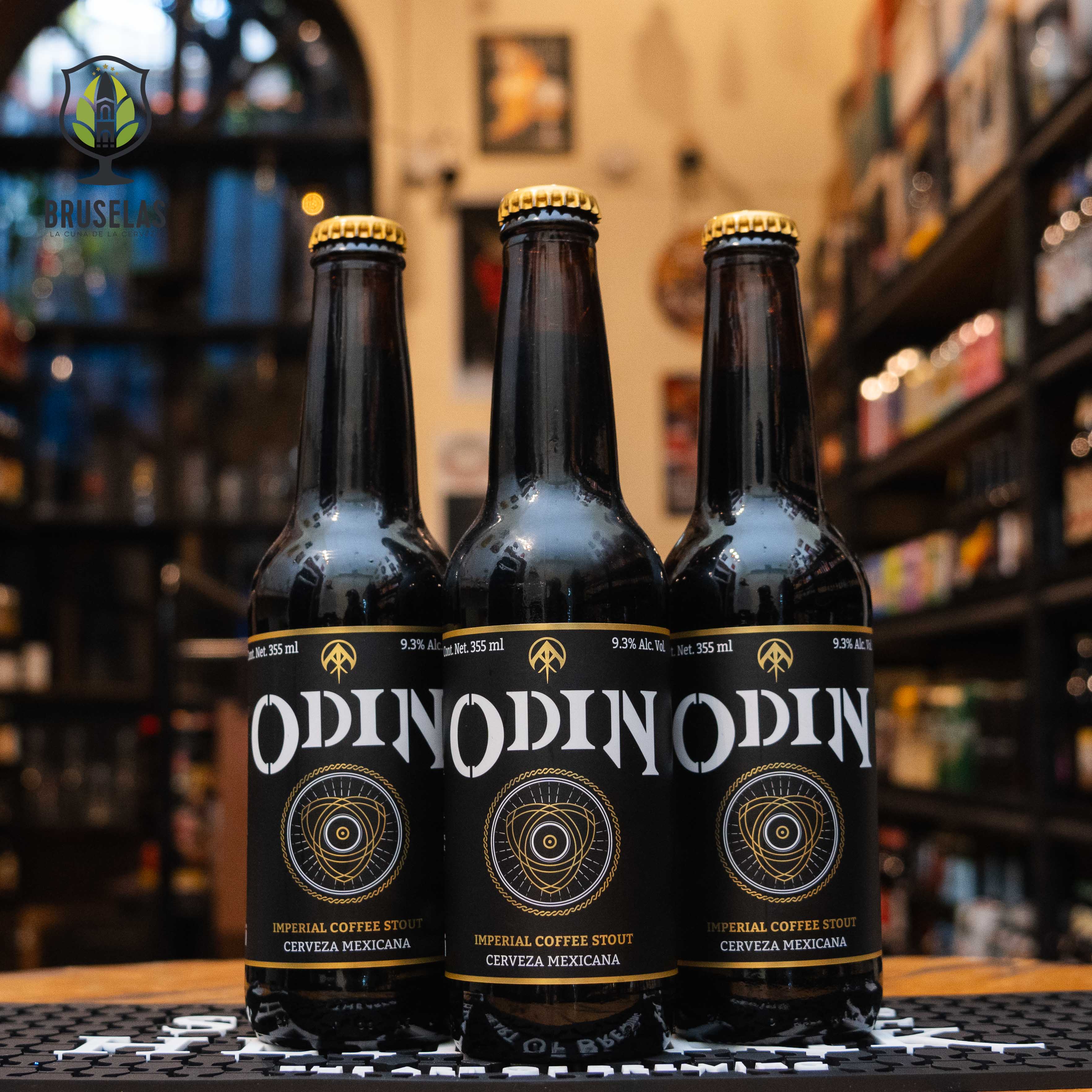 Botella de Rámuri Odin, una cerveza artesanal estilo Imperial Coffee Stout elaborada por Cervecería Rámuri en Tijuana, Baja California, México. La etiqueta es negra con detalles dorados y el nombre "Odin" en tipografía blanca prominente. Presenta un ABV de 9.3%, ofreciendo aromas intensos a café tostado y chocolate oscuro, con un cuerpo sedoso y un final largo y ligeramente amargo. Ideal para acompañar postres de chocolate, carnes asadas y quesos fuertes.