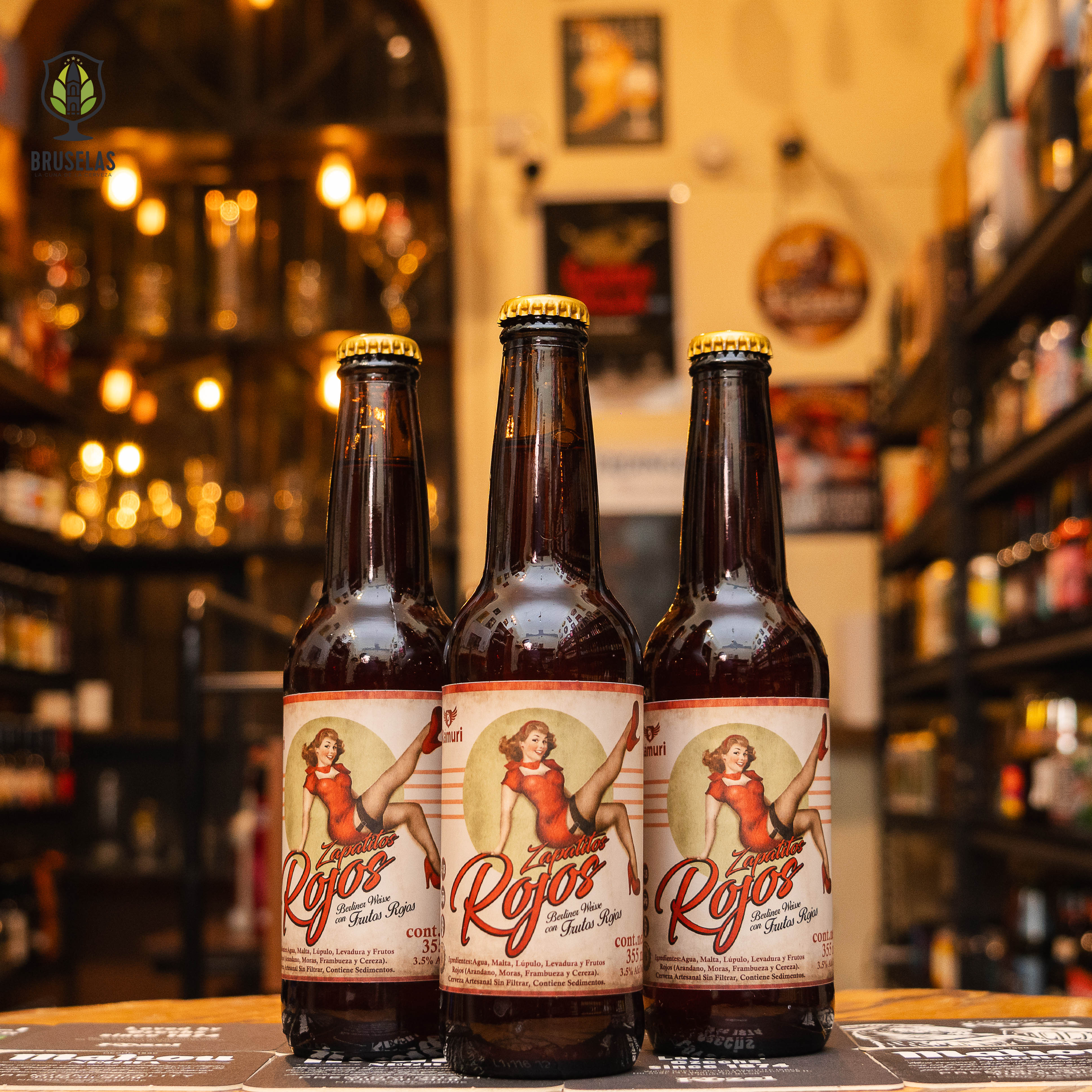 Botellas de Zapatitos Rojos, una Berliner Weisse afrutada de Cervecería Rámuri, con un ABV de 3.8%. Presenta un atractivo color rosado y aromas de frutos rojos como zarzamoras, frambuesas, arándanos y fresas. Su sabor ofrece un equilibrio entre acidez y dulzura frutal, con una textura ligera. Ganadora de oro en la Brasil Beer Cup. Ideal para maridar con carnes sazonadas, postres y mousse de chocolate.