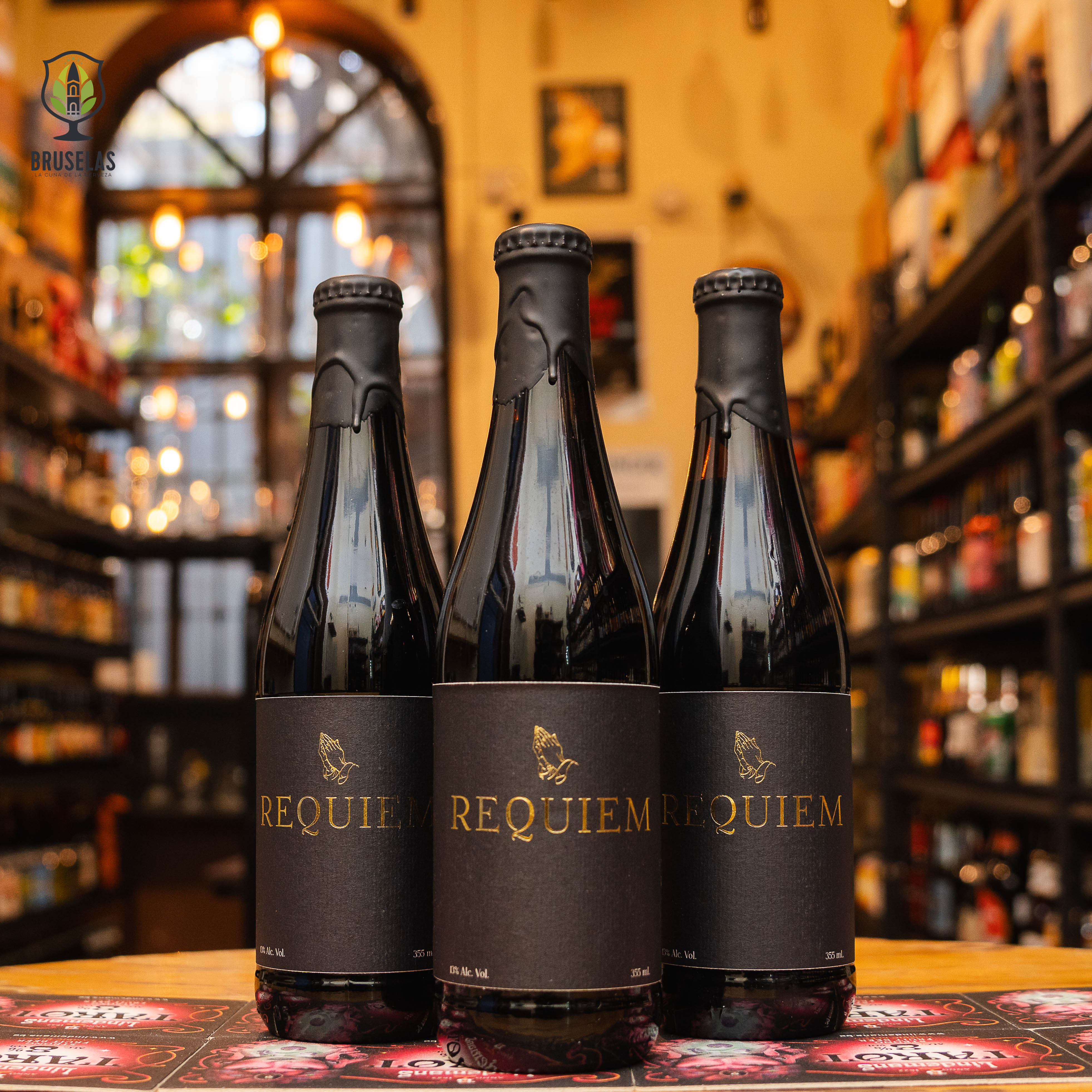 Botella de Santa Sabina Requiem, una Russian Imperial Stout de Santa Sabina Brewery con un ABV de 13% y 40 IBU. Añejada 12 meses en barricas de whisky de centeno, ofrece sabores a chocolate oscuro, café tostado y un toque ahumado, complementado con la dulzura de las barricas. Perfecta para maridar con carnes asadas, postres de chocolate o disfrutar como digestivo.