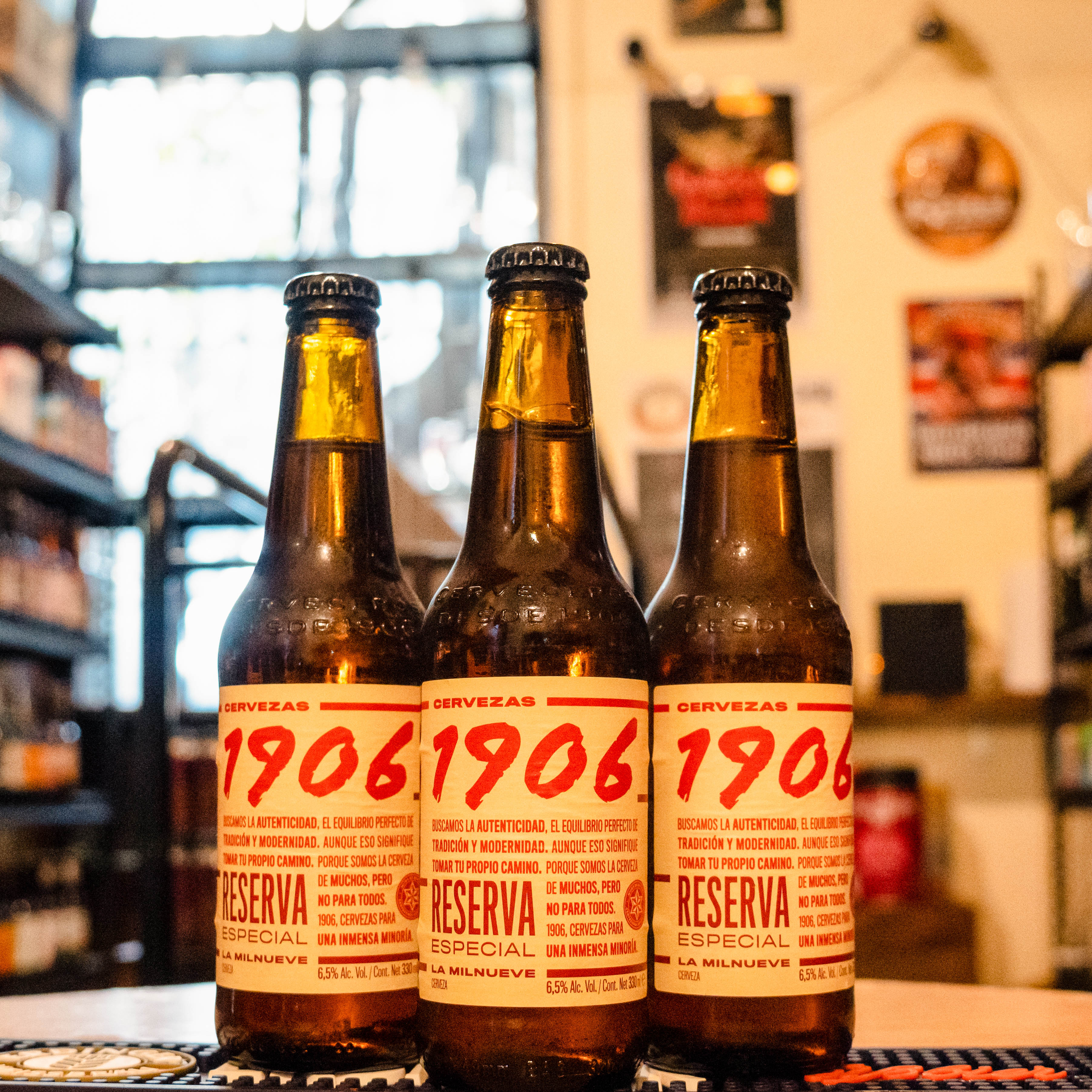 Botella de 1906 Reserva Especial, una Helles Bock de Estrella Galicia con un ABV de 6.5% y 25 IBU. Presenta un color ámbar brillante y aromas de malta tostada, caramelo y café. Su sabor es equilibrado, con toques de frutas maduras y un final ligeramente amargo. Ideal para maridar con carnes rojas, embutidos, quesos curados y pescados. Refleja robustez y elegancia en cada sorbo.