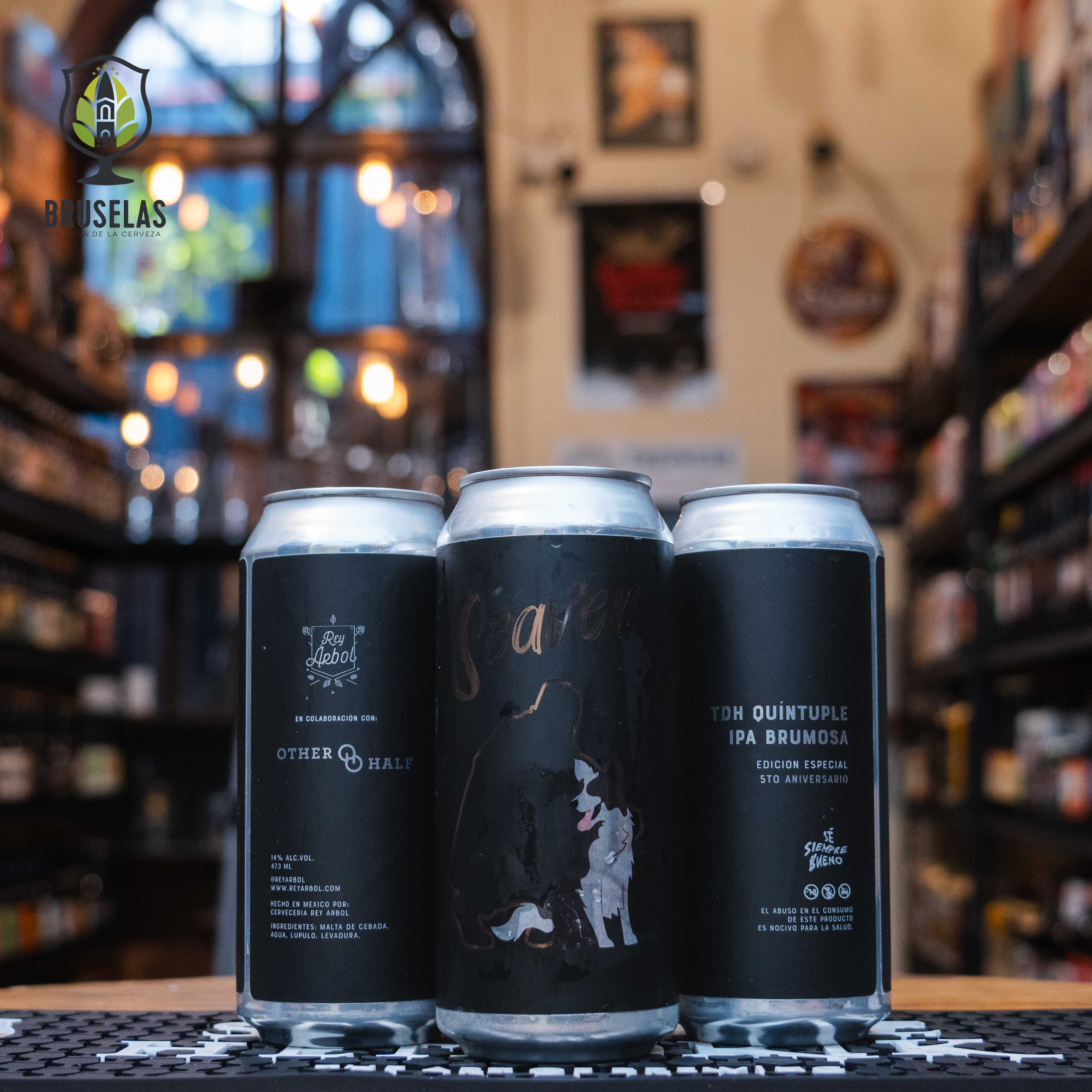 Lata de Seaver (5to Aniversario), una Quíntuple IPA Brumosa (TDH) de Cervecería Rey Árbol en colaboración con Other Half Brewing. La etiqueta es negra con ilustraciones sutiles de siluetas en dorado. Con un ABV de 14%, esta cerveza ofrece intensas notas frutales de mango y piña, con un amargor equilibrado. Ideal para acompañar carnes asadas o quesos fuertes. El diseño refleja la sofisticación y robustez de una edición especial.