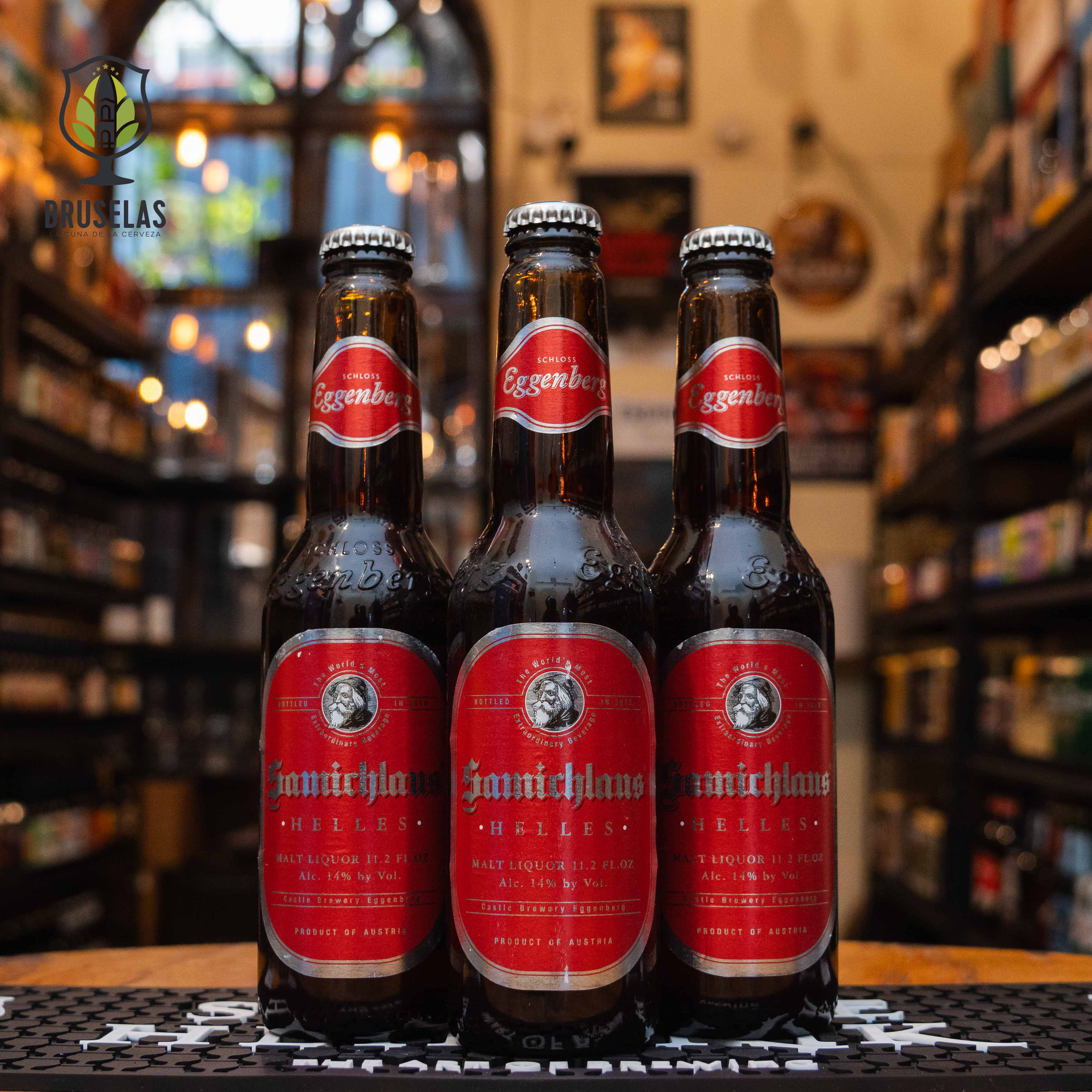 Botella de Samichlaus Helles, una Doppelbock lager de Brauerei Schloss Eggenberg, Austria. La etiqueta es roja con detalles dorados y una imagen histórica en el centro. ABV de 14%, con aromas de malta dulce, caramelo y frutas maduras. Sabor rico y dulce con un final cálido. Ideal para acompañar postres de frutas, quesos curados o como digestivo. Diseño clásico y robusto.