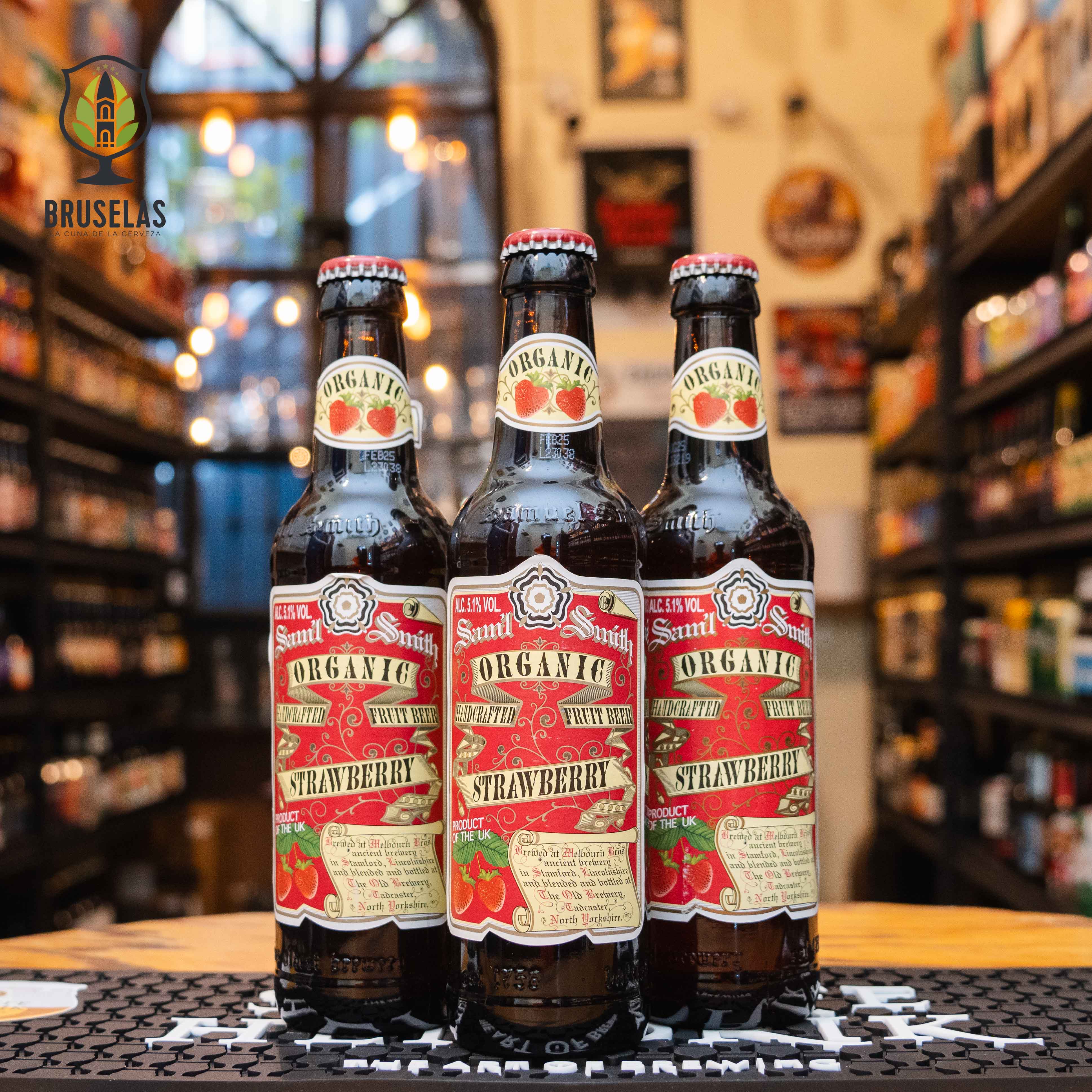 Botella de Samuel Smith Organic Strawberry, una Fruit Beer inglesa elaborada con ingredientes orgánicos por Samuel Smith Old Brewery. La etiqueta es roja con detalles de fresas y letras clásicas. ABV de 5.1%, con aromas de fresas frescas y malta ligera. Sabor dulce y afrutado con un final refrescante. Ideal para acompañar postres de frutas, tartas y ensaladas con queso de cabra.