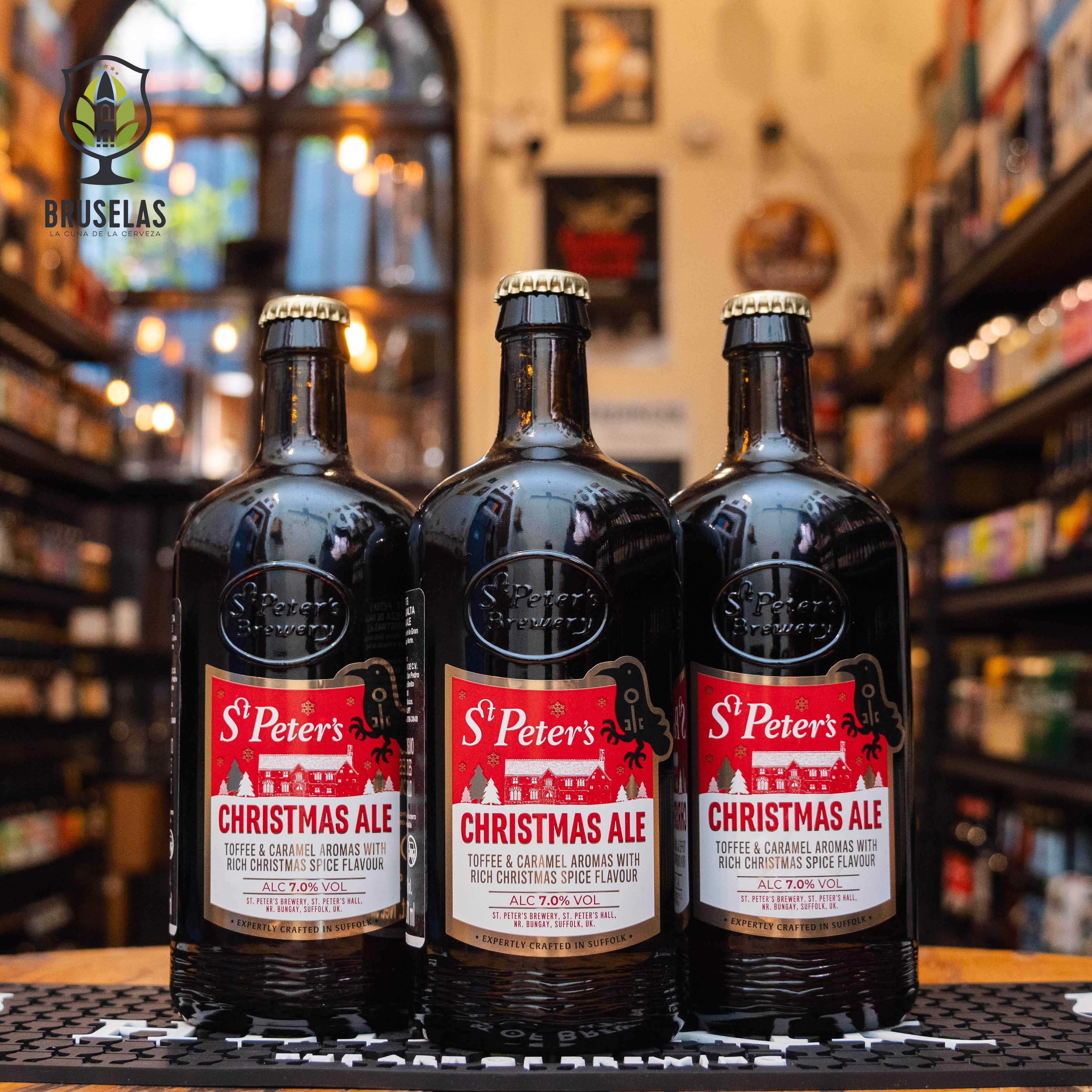 Botella de St. Peter's Christmas Ale, una Winter Ale de St. Peter's Brewery, con un ABV de 7%. La etiqueta presenta un diseño navideño con detalles rojos y blancos. Su perfil aromático incluye toffee, caramelo y especias. Sabor dulce y afrutado con un final cálido. Ideal para acompañar platillos navideños y quesos añejos.