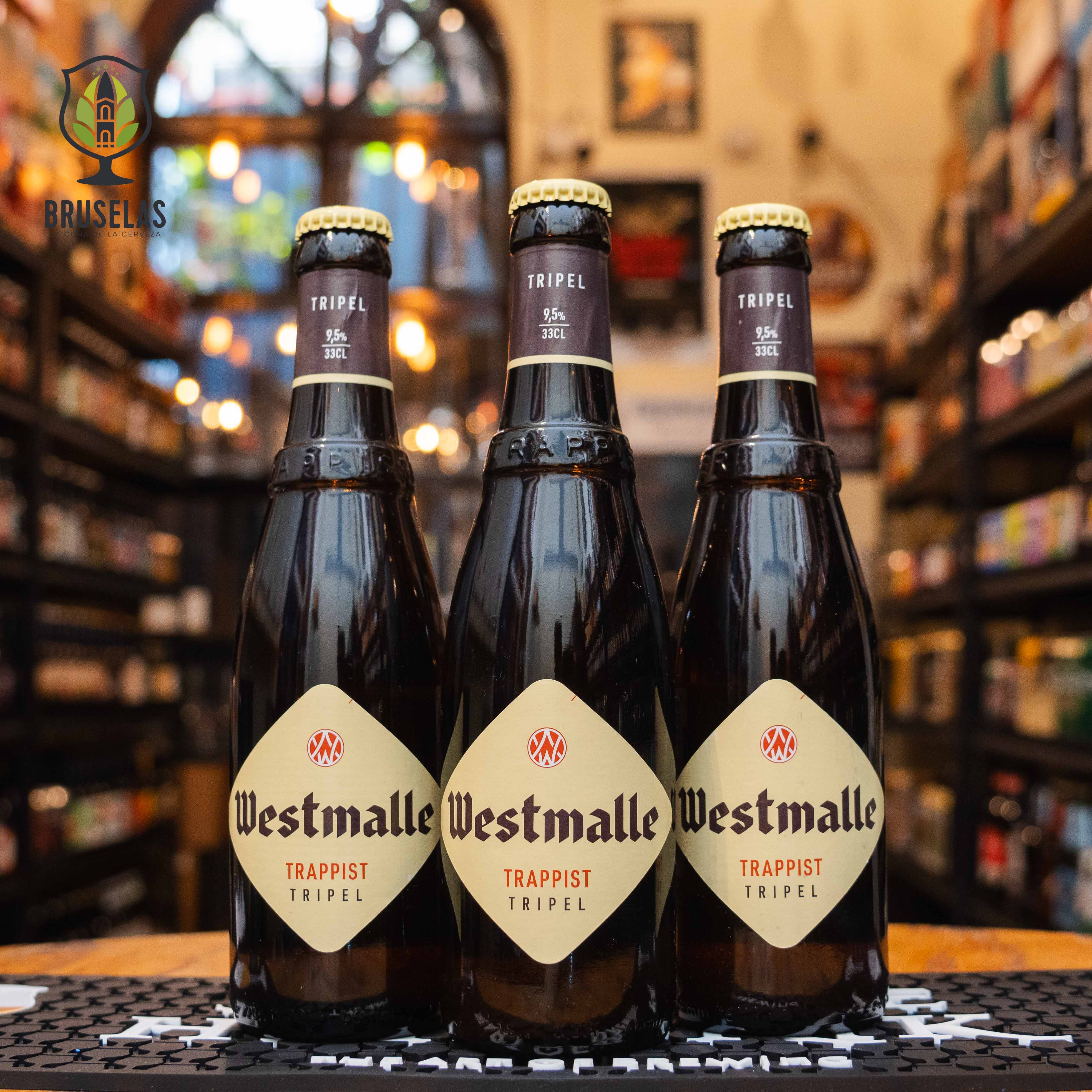 Botella de Westmalle Tripel, una cerveza trapense belga de estilo Belgian Tripel. La etiqueta es beige con el logo trapense. ABV de 9.5%. Sabor equilibrado con notas de plátano maduro, especias y un amargor refinado, con un final seco. Ideal para acompañar quesos ricos, platos de caza y guisos contundentes. El diseño refleja la herencia cervecera de la Abadía de Westmalle.