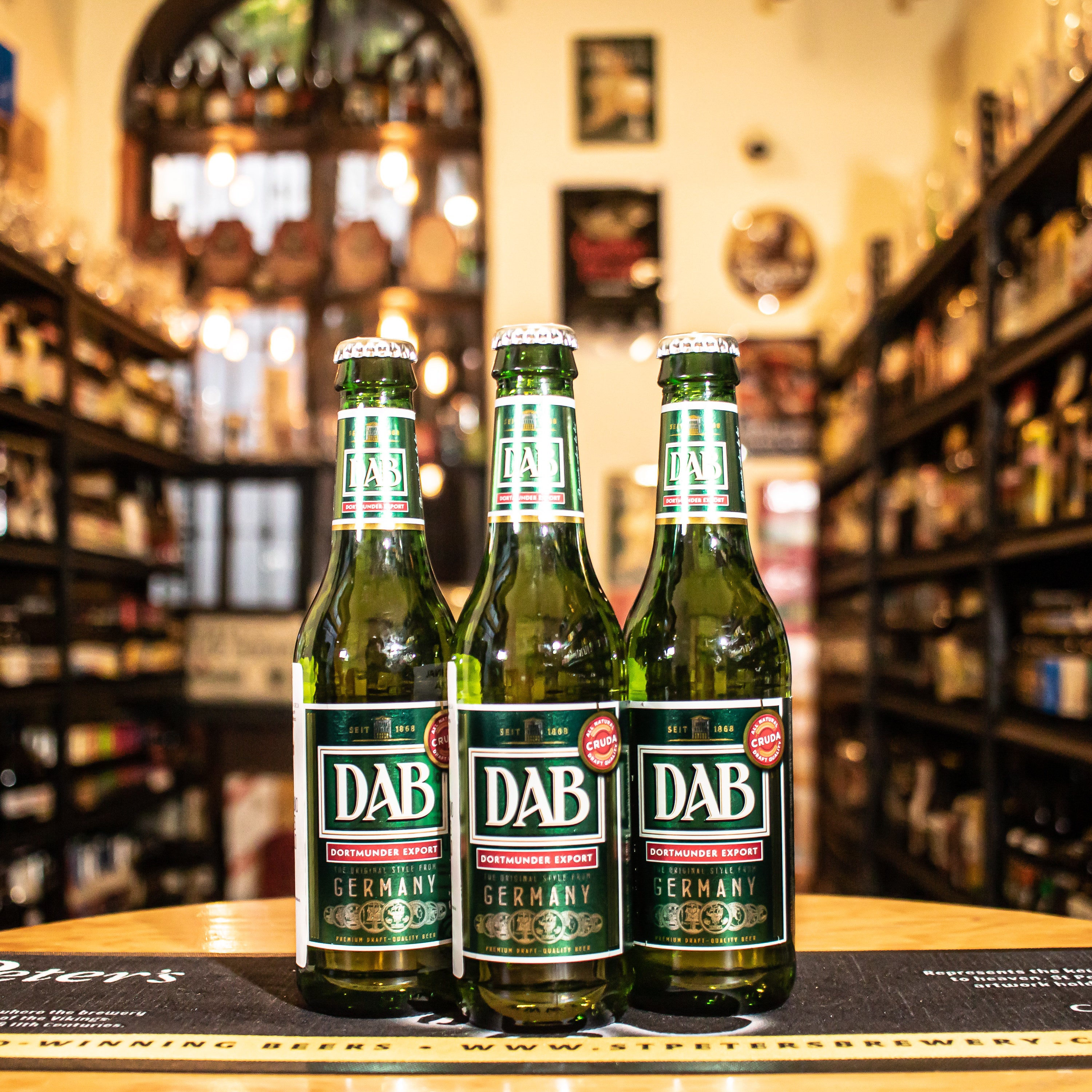 Botella de DAB Export de 330 ml, una lager alemana clásica elaborada por Dortmunder Actien Brauerei. Con un ABV de 5.0%, esta cerveza presenta un color dorado brillante y una claridad impecable. Su sabor es suave y equilibrado, con sutiles notas de malta y un ligero amargor al final, ofreciendo una experiencia refrescante. Ideal para maridar con ensaladas, pescados y carnes blancas, es perfecta para quienes buscan una cerveza ligera y fácil de beber.