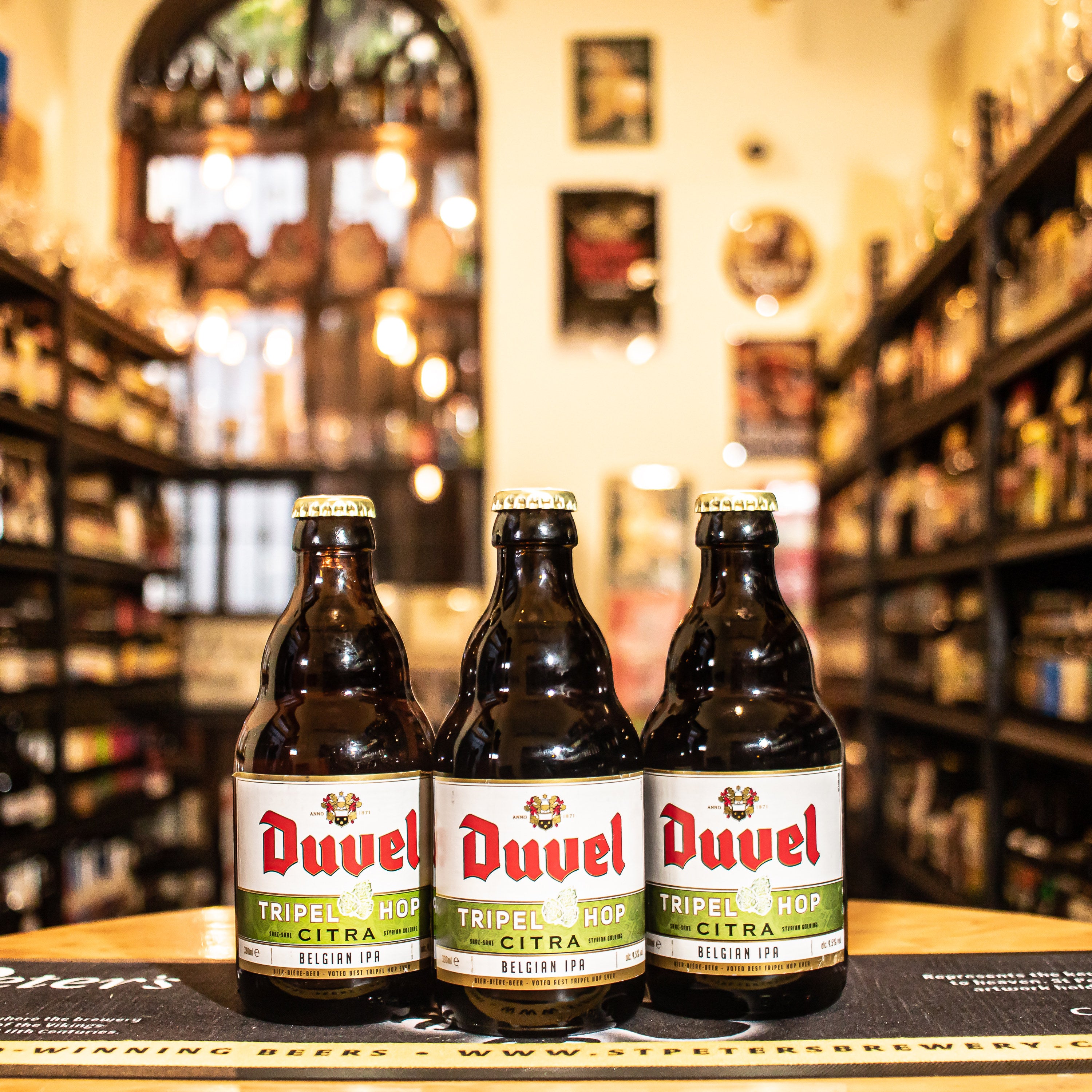 Botella de Duvel Tripel Hop Citra, una edición especial de la clásica Duvel elaborada por Duvel Moortgat, catalogada como una Belgian IPA. Con un ABV de 9.5%, incorpora el lúpulo Citra, que aporta frescas notas cítricas y tropicales como mango y papaya. En boca, es vibrante y lupulada, con un amargor pronunciado equilibrado por sabores frutales y un final seco. Ideal para maridar con platos especiados, mariscos y quesos fuertes. Presentación en botella de 330 ml.