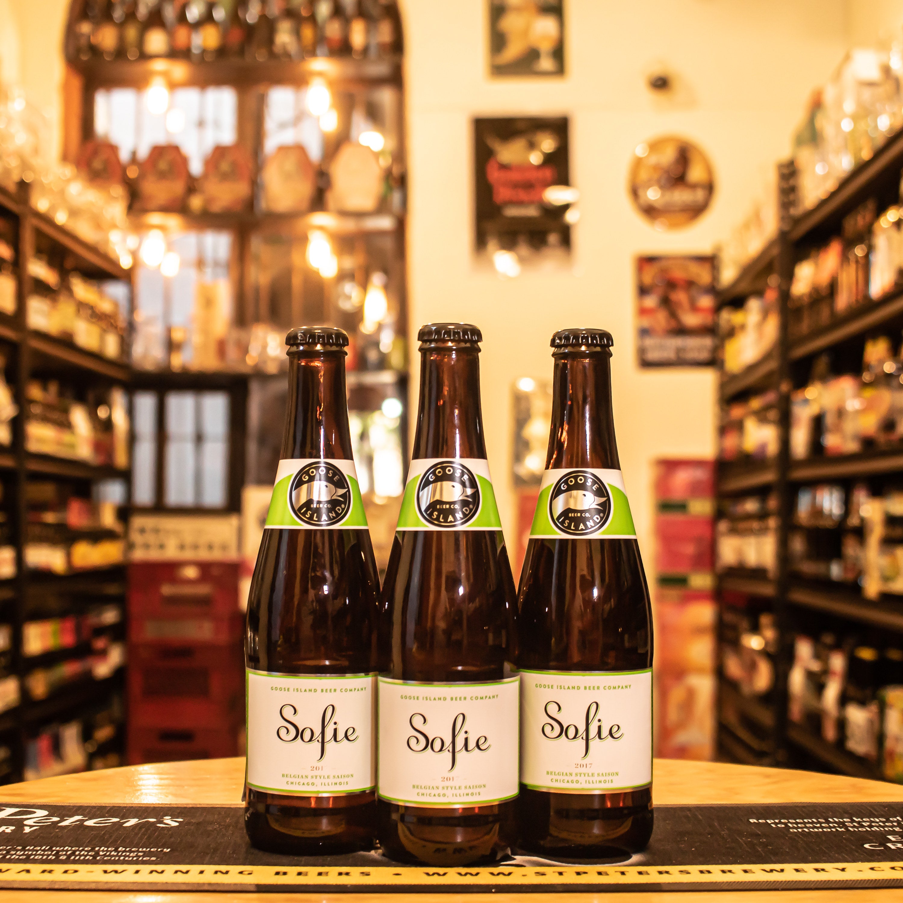 Botella de Goose Island Sofie, una Belgian Farmhouse Ale (Saison) de Goose Island Beer Co. La etiqueta presenta un diseño elegante con detalles en tonos claros que reflejan su carácter fresco. Con un ABV de 6.5%, ofrece aromas cítricos, especias y un toque de vainilla. Su sabor es refrescante, con una ligera acidez y notas especiadas. Ideal para maridar con mariscos, ensaladas y quesos suaves. Perfecta para quienes buscan una cerveza sofisticada y compleja.