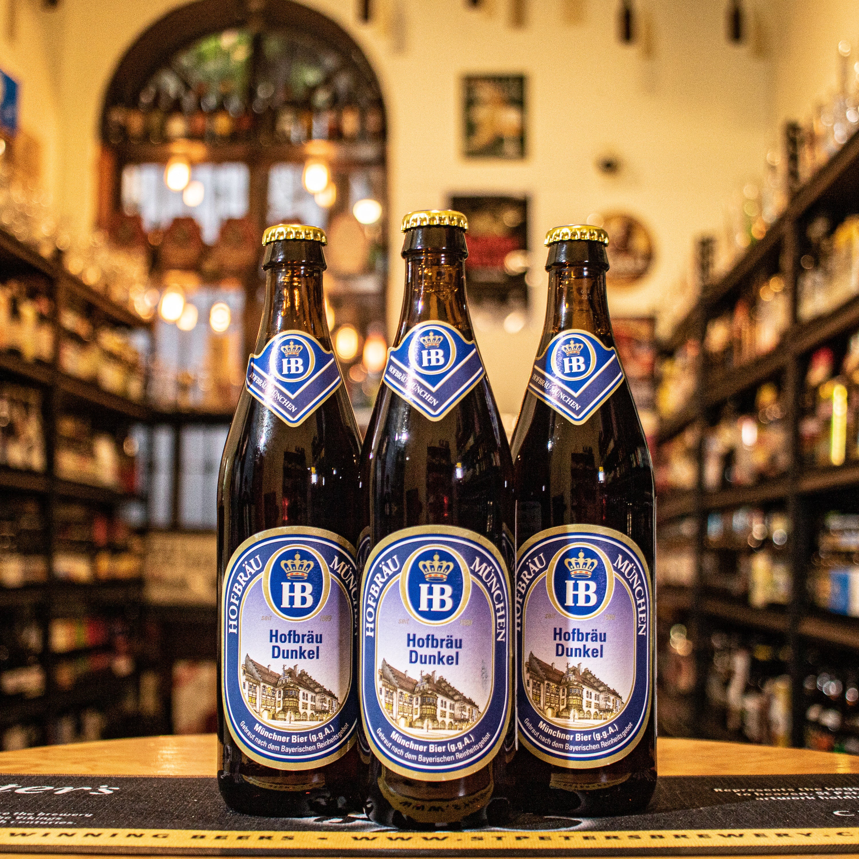 La Hofbräu Dunkel es una cerveza de estilo Dunkel elaborada por la cervecería Hofbräuhaus München. Con un ABV de 5.5%, destaca por su color marrón oscuro con reflejos rojizos. En su perfil, predominan las notas de malta tostada, caramelo y chocolate, con un toque de dulzor ligero. Es ideal para maridar con carnes rojas, platos a la parrilla y quesos maduros, lo que la convierte en una opción rica y compleja para los amantes de las cervezas oscuras.