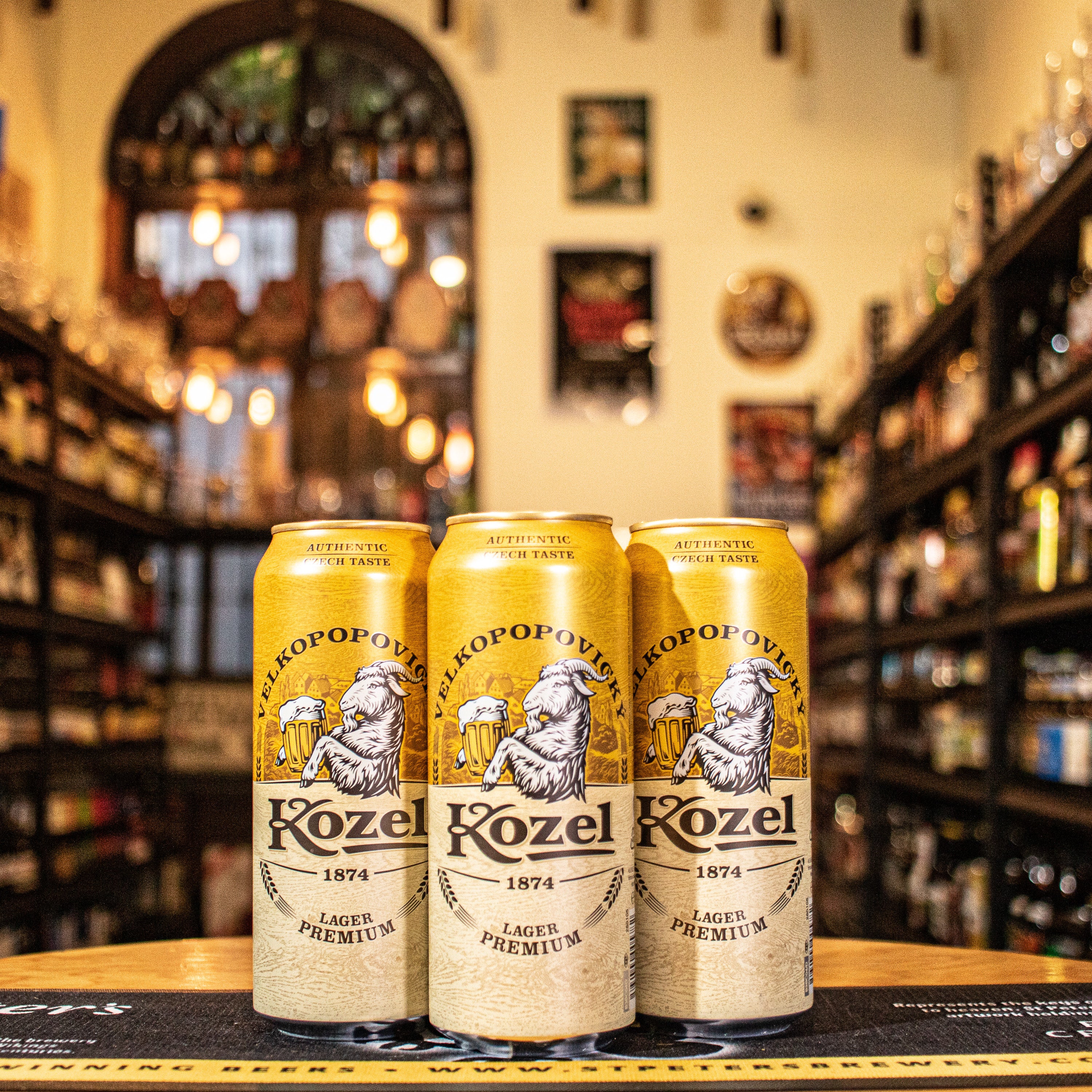 Lata de Kozel Premium Lager, una lager checa de la cervecería Velkopopovický Kozel. Con un ABV de 4.6%, presenta un color dorado brillante y espuma blanca persistente. Ofrece aromas de malta fresca, lúpulo y un toque herbáceo. Su sabor es suave y equilibrado, con un amargor sutil y un final refrescante. Ideal para maridar con carnes a la parrilla, salchichas y quesos suaves. Diseño clásico y fresco.