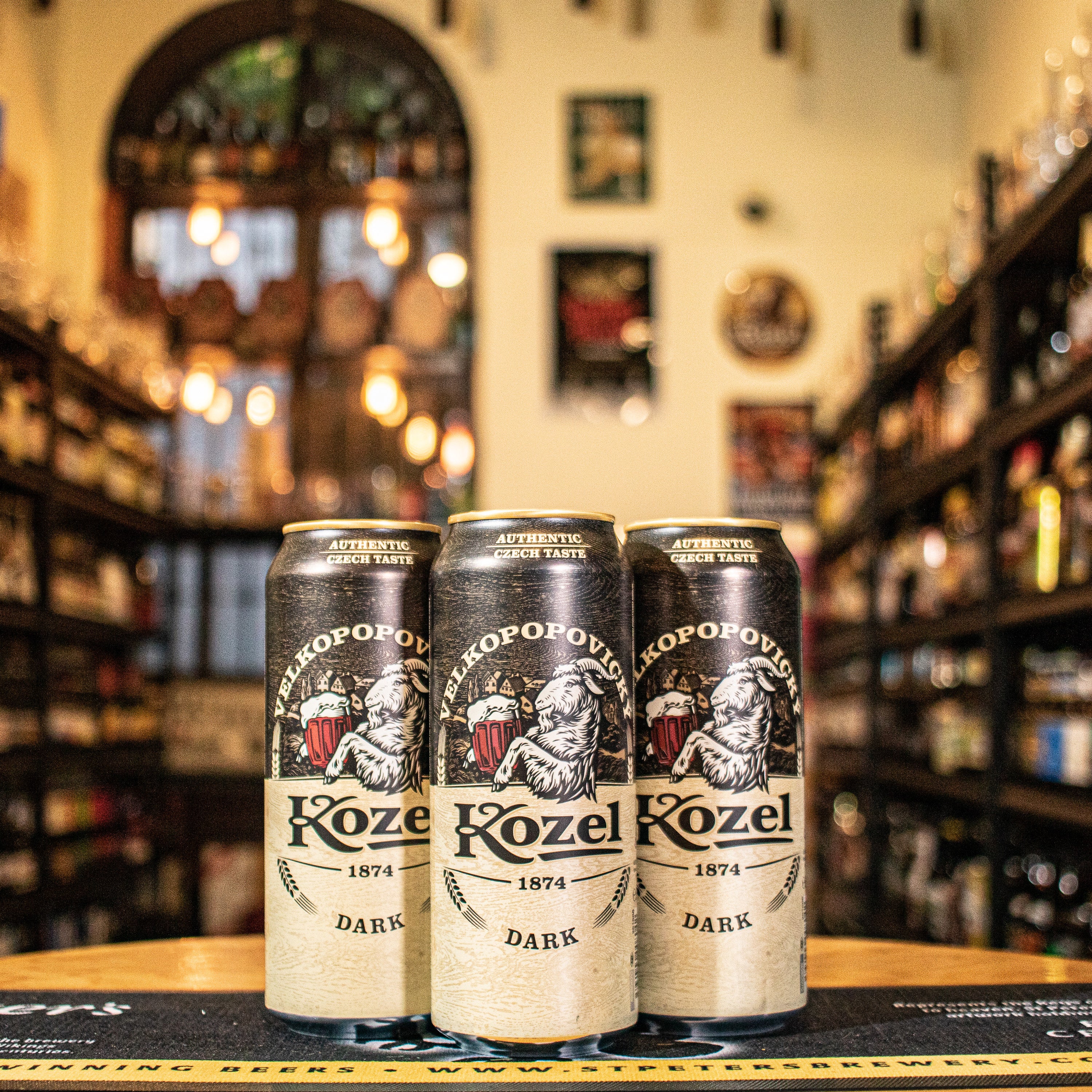 Lata de Kozel Dark, una Dark Lager checa de la cervecería Velkopopovický Kozel. Con un ABV de 3.8%, presenta un color caoba profundo y espuma cremosa. Ofrece aromas de malta tostada, caramelo y un toque de café. Su sabor es dulce y suave, con un ligero amargor y un final limpio. Ideal para maridar con carnes asadas, quesos maduros y postres de chocolate. Su diseño refleja tradición y suavidad.