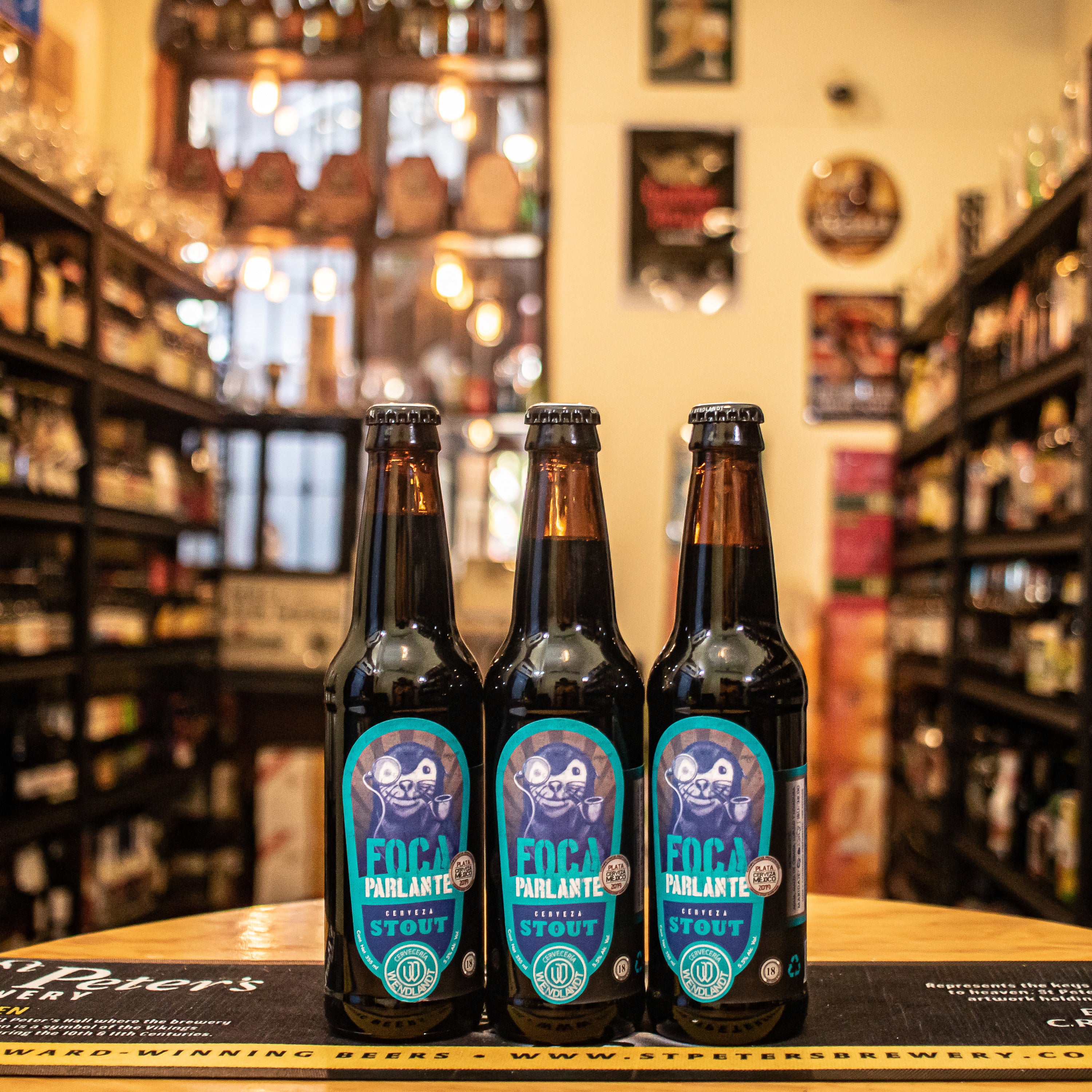 Botella de Foca Parlante, una stout artesanal mexicana elaborada por Cervecería Wendlandt en Ensenada, Baja California. La etiqueta presenta un diseño oscuro y moderno. ABV de 5.5%, con aromas a maltas tostadas, café espresso y chocolate amargo. Cuerpo medio y textura cremosa. Ideal con carnes ahumadas, quesos fuertes y postres de chocolate. Refleja un estilo robusto y equilibrado.